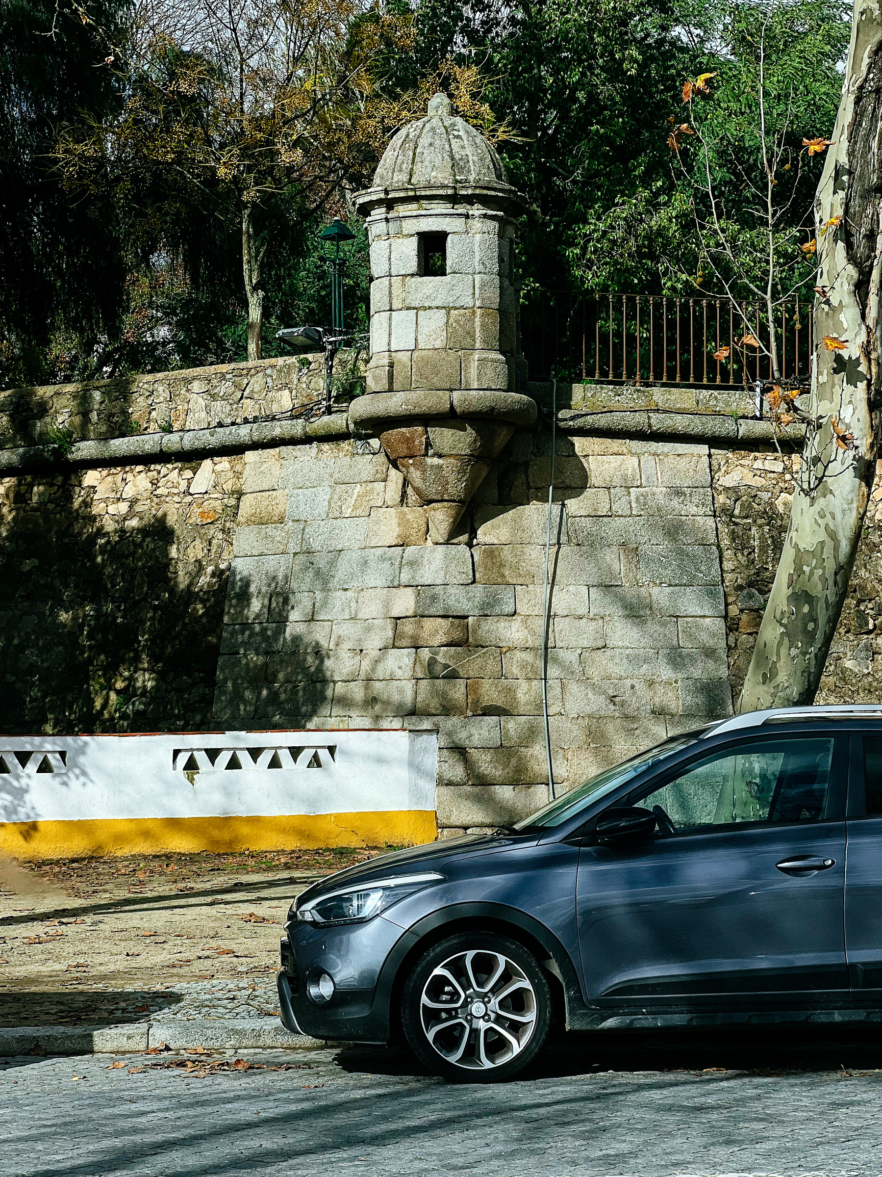 A car is parked in front of the city’s rampart. A watch tower is visible. 