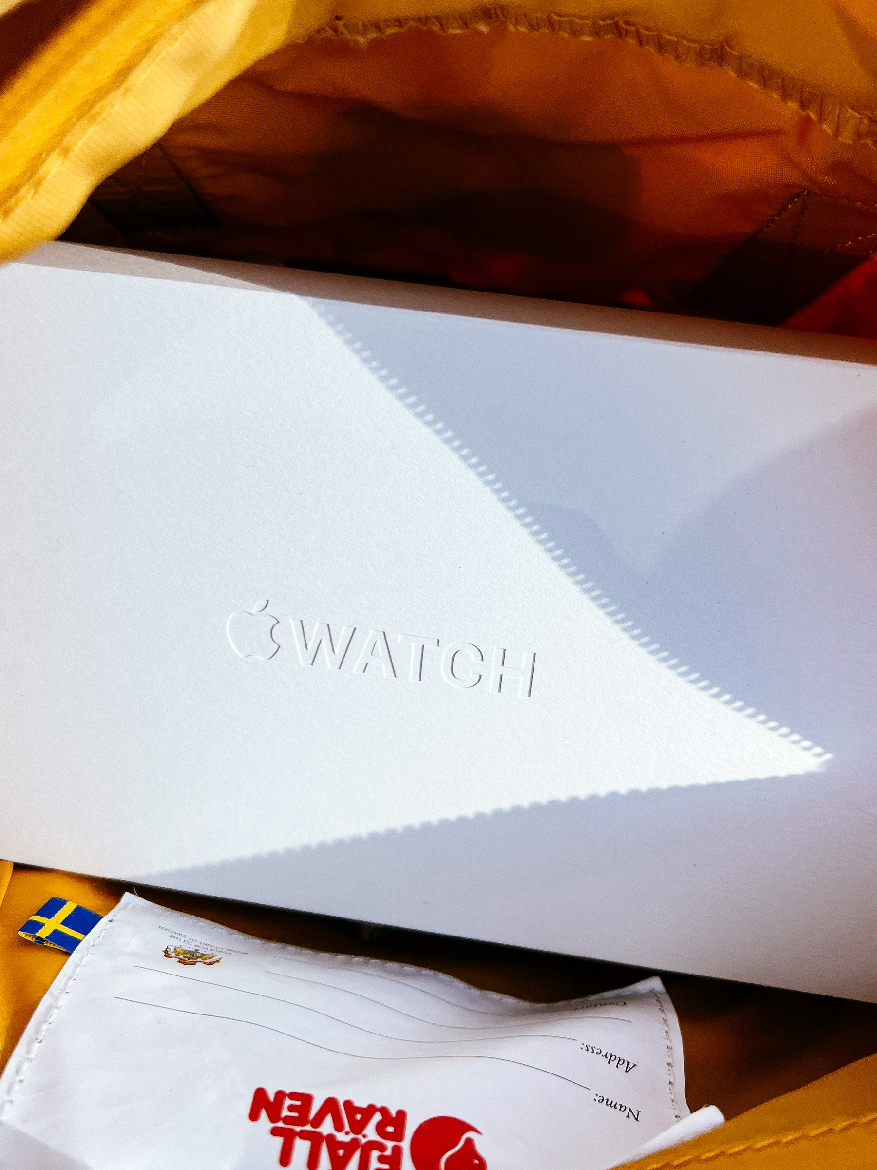 Looking down into a backpack, you can see the box of an Apple Watch