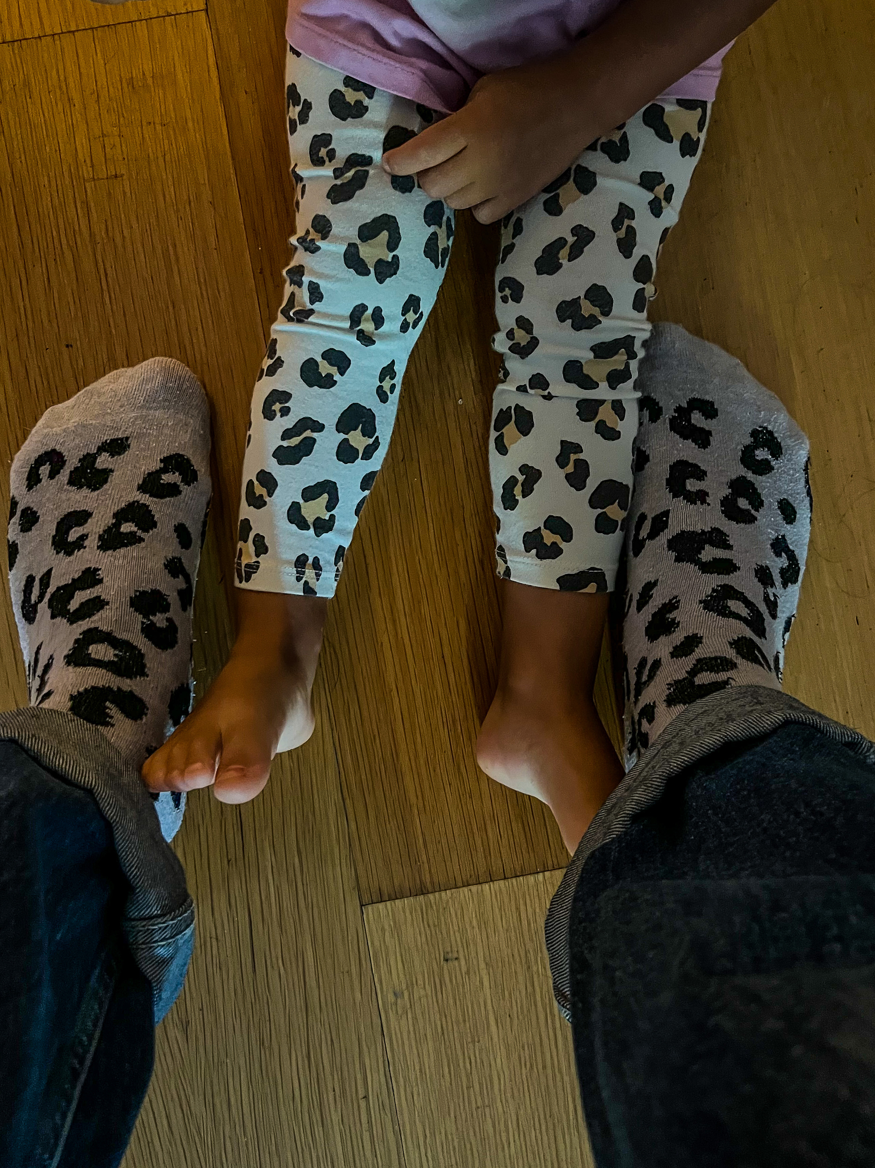 looking down we see a toddler’s legs and a grownup’s legs. Both are wearing leopard print items