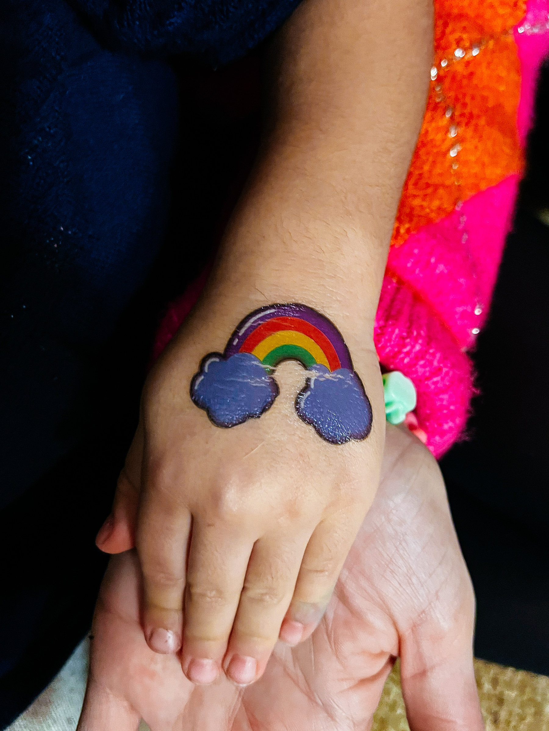Temporary tattoo, a rainbow, in a child’s hand. 