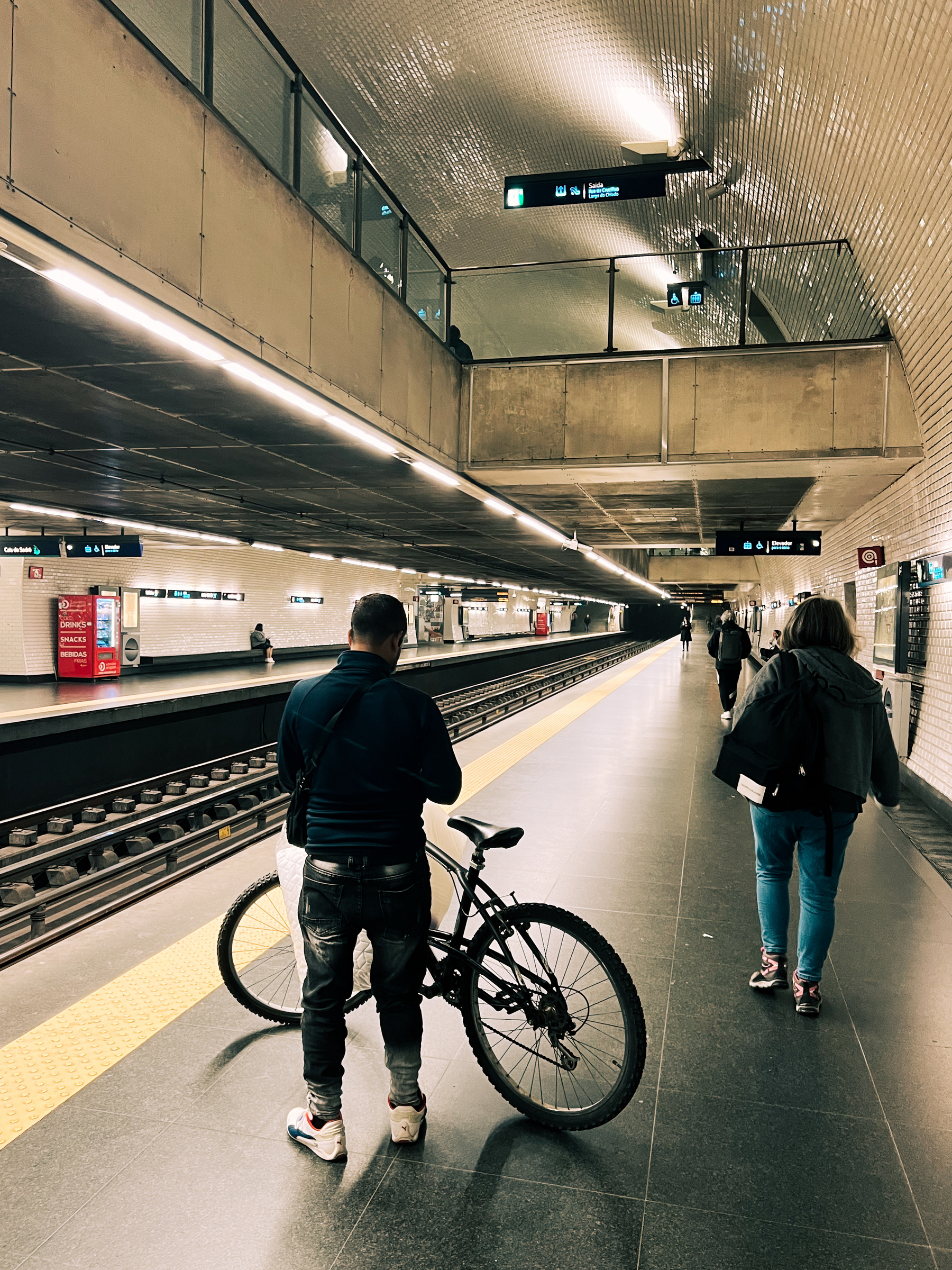 A man with a bicycle on the subway platform. 