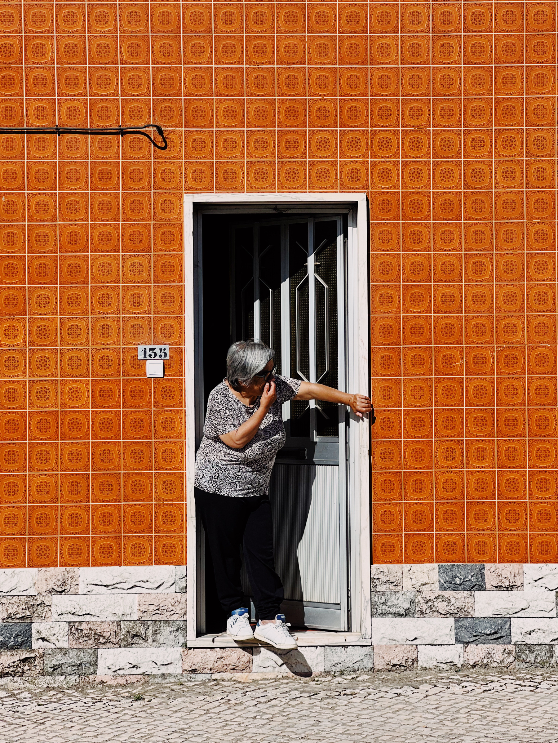 A woman look out the door, on a orange tiled house. 