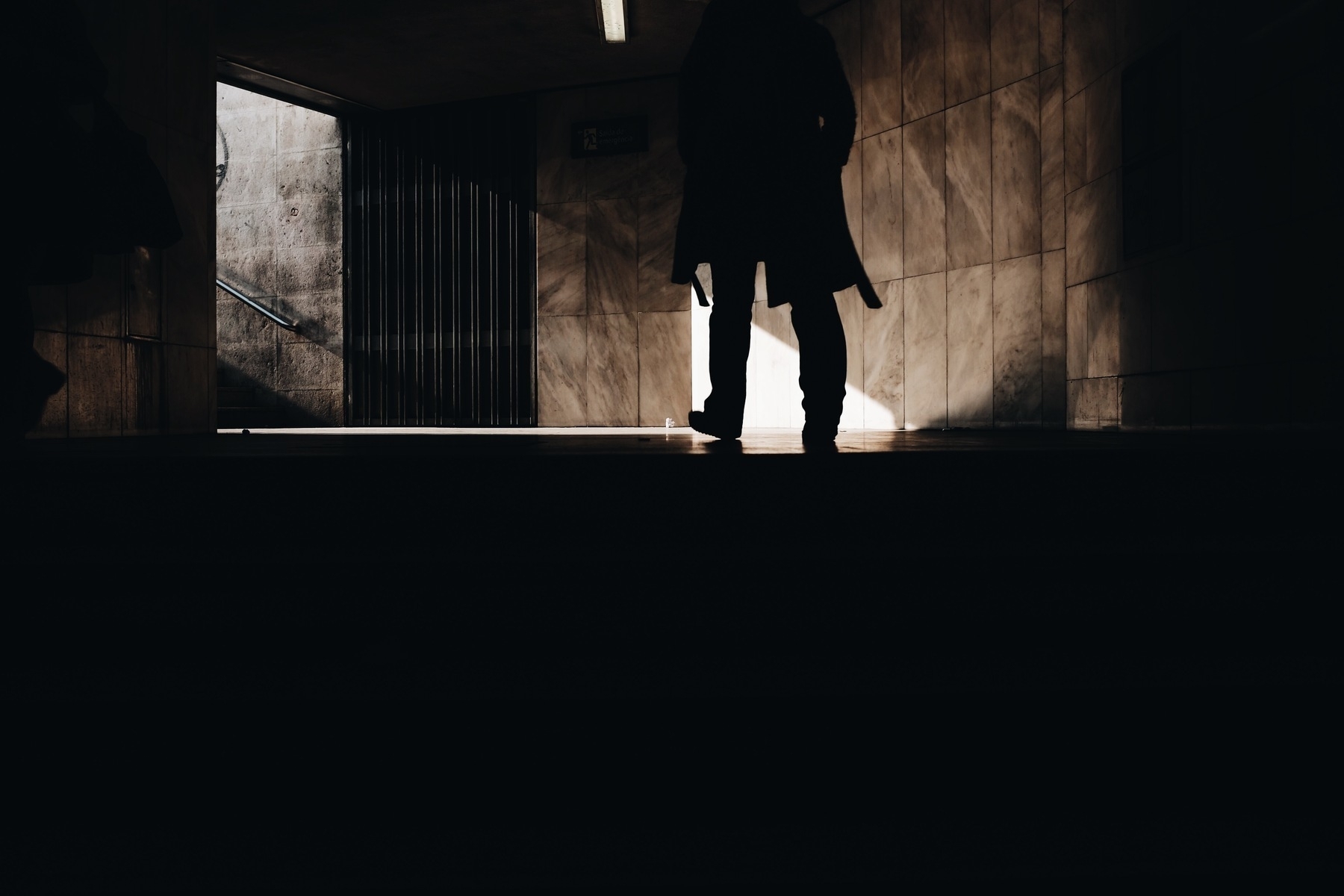 Dark photo showing a man walking towards an exit of the darkness.