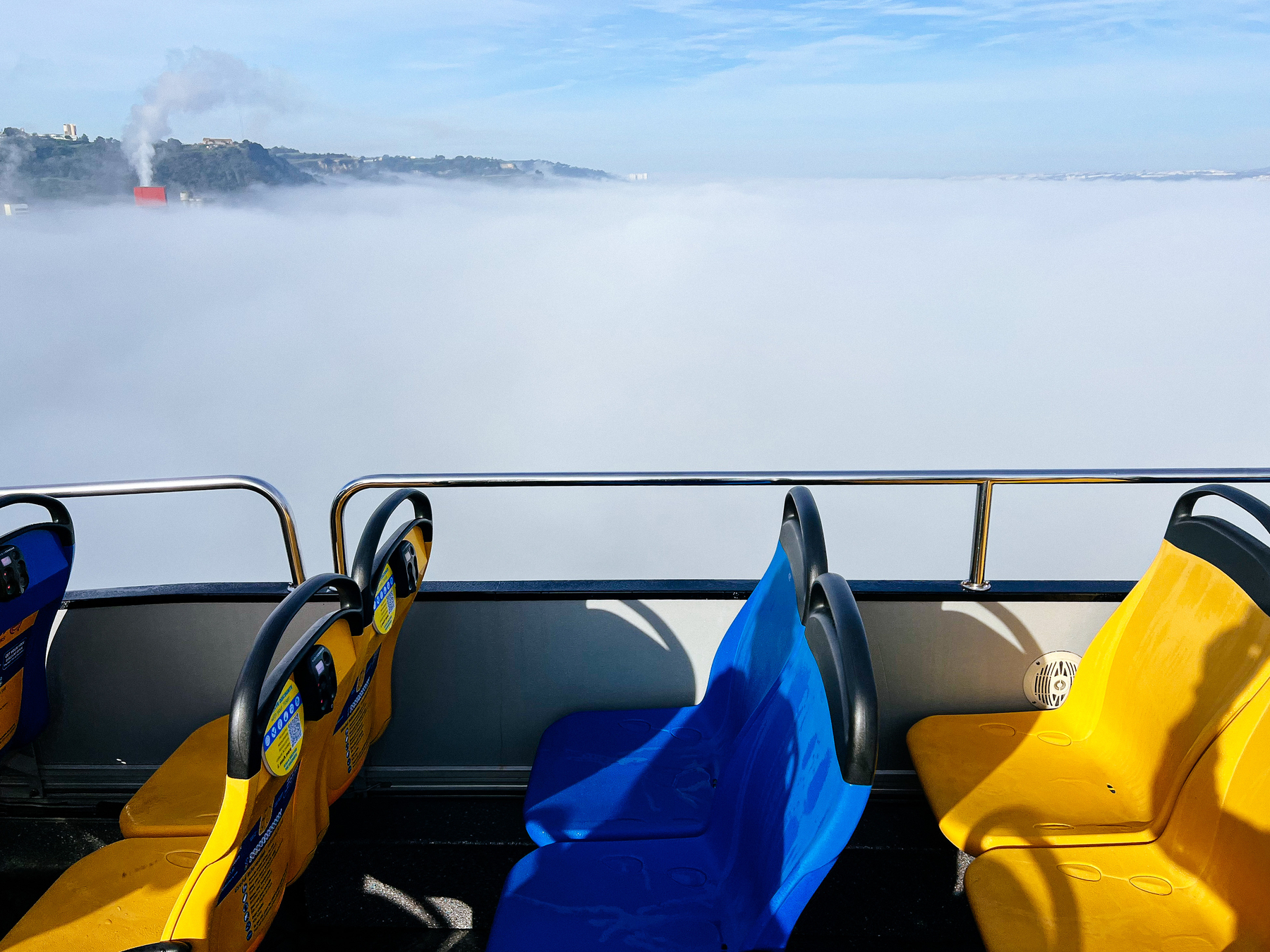foggy horizon, as seen from a moving bus. Yellow and blue seats visible in the foreground.