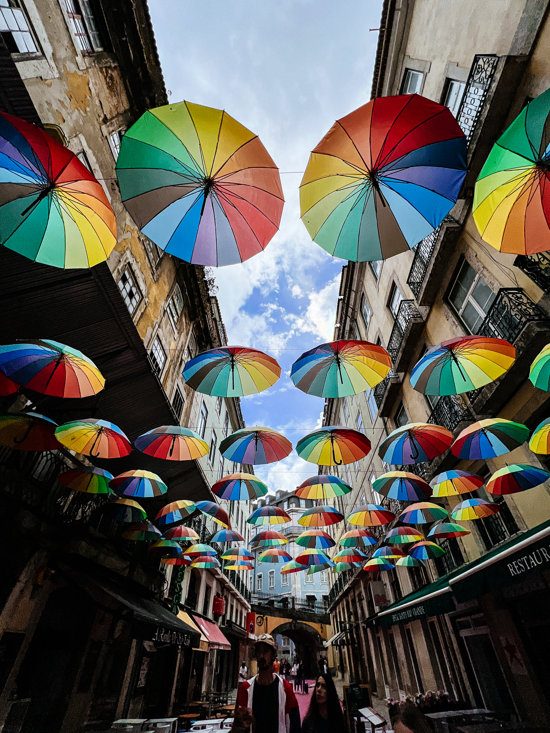 Rainbow coloured umbrellas on a street.