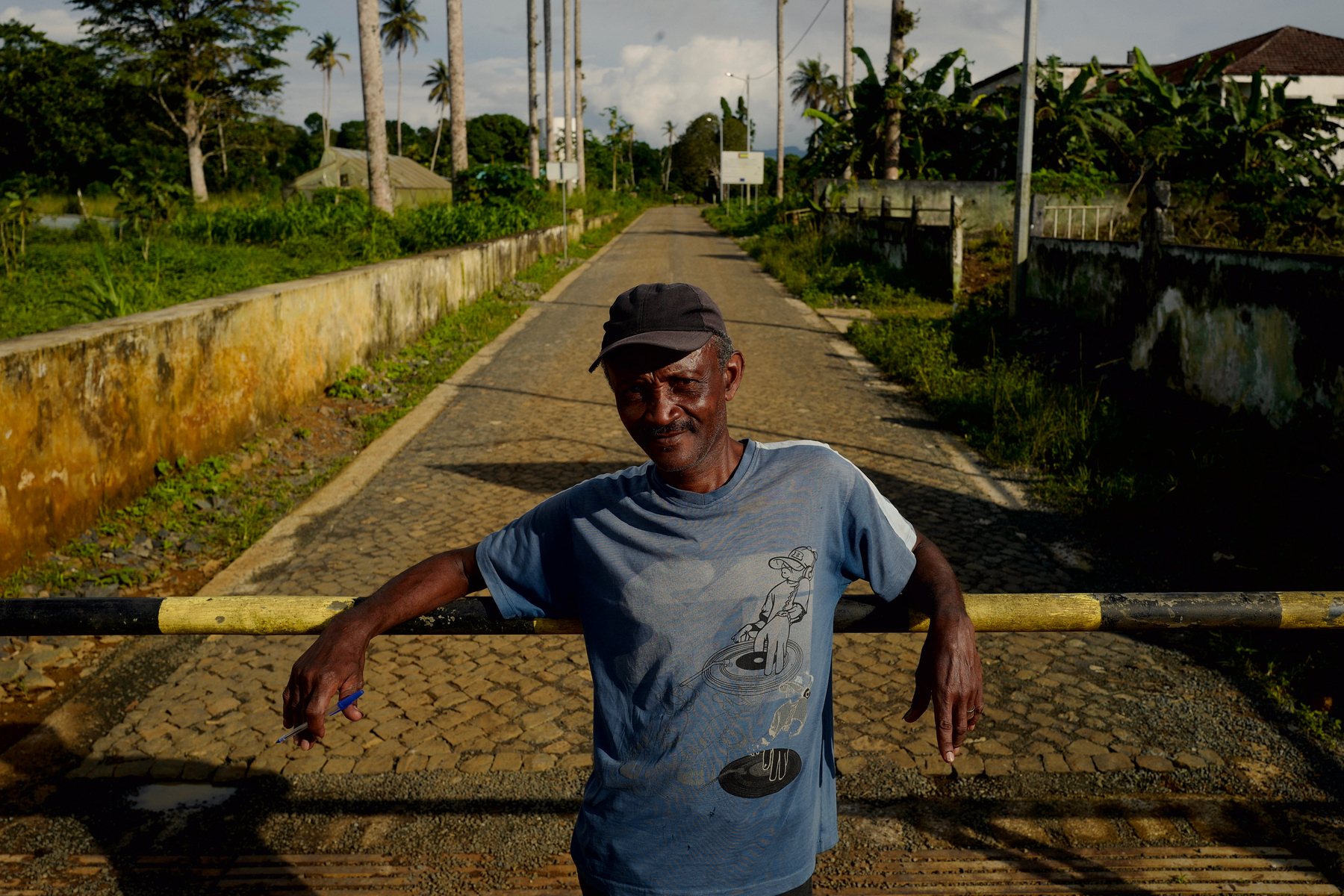 A man leans against a fence, at the end of a road. 
