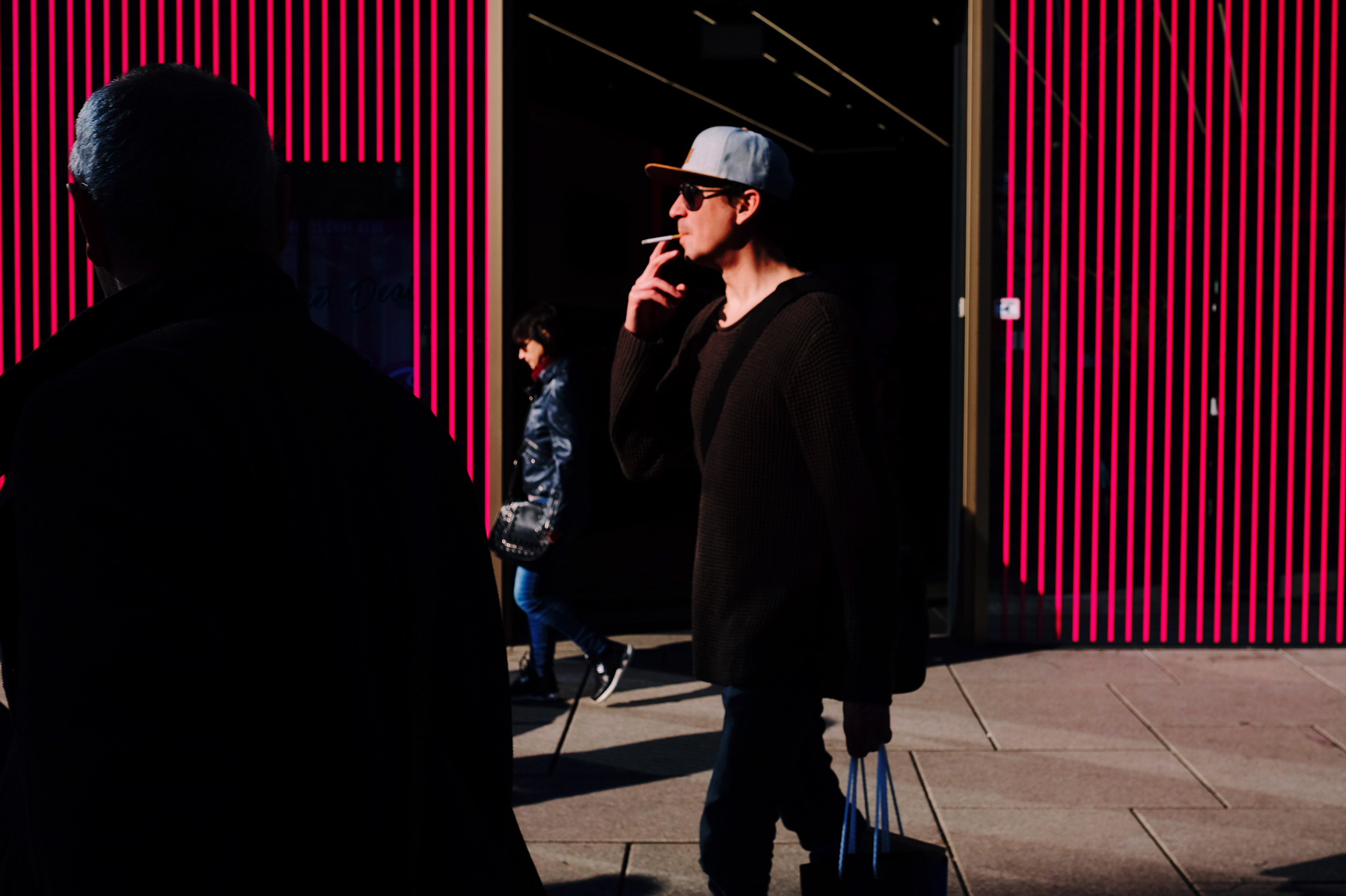A man walks by, smoking a cigarette. 