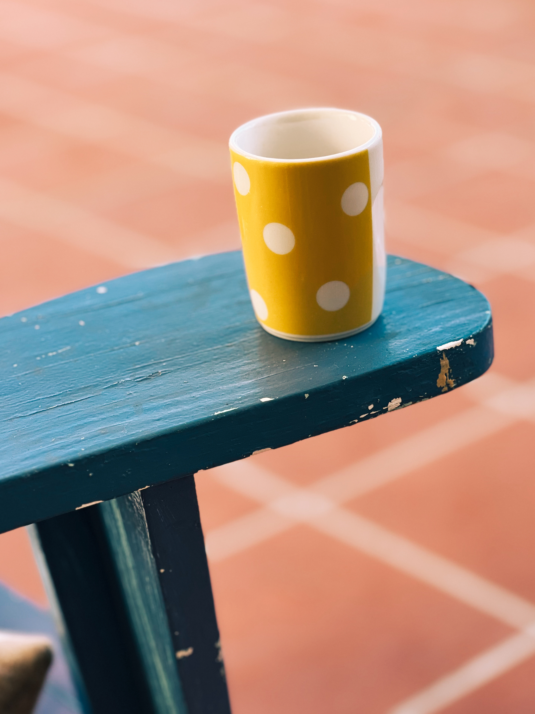 A yellow coffee cup standing on a blue chair. 