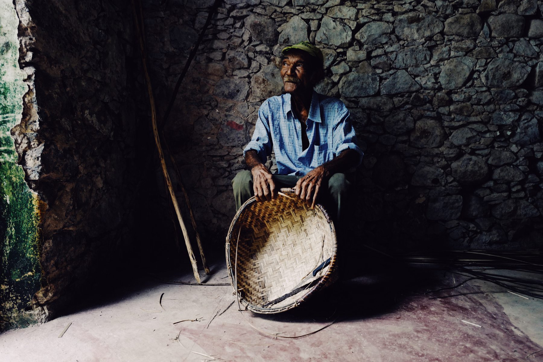 A man sits with a basket he just made. 