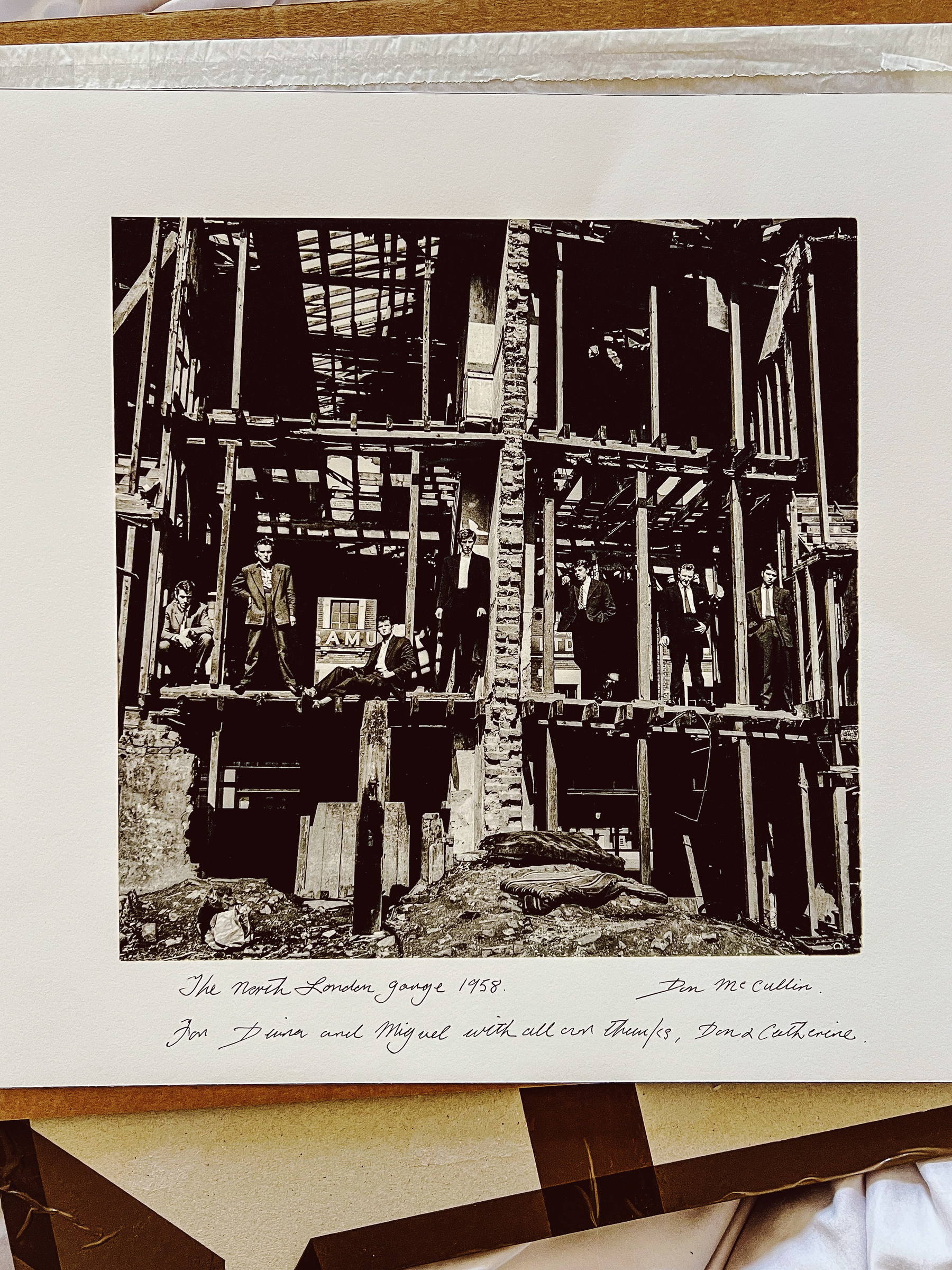 A black and white print, of a famous Don McCullin photo. Men are standing in a gutted building. 