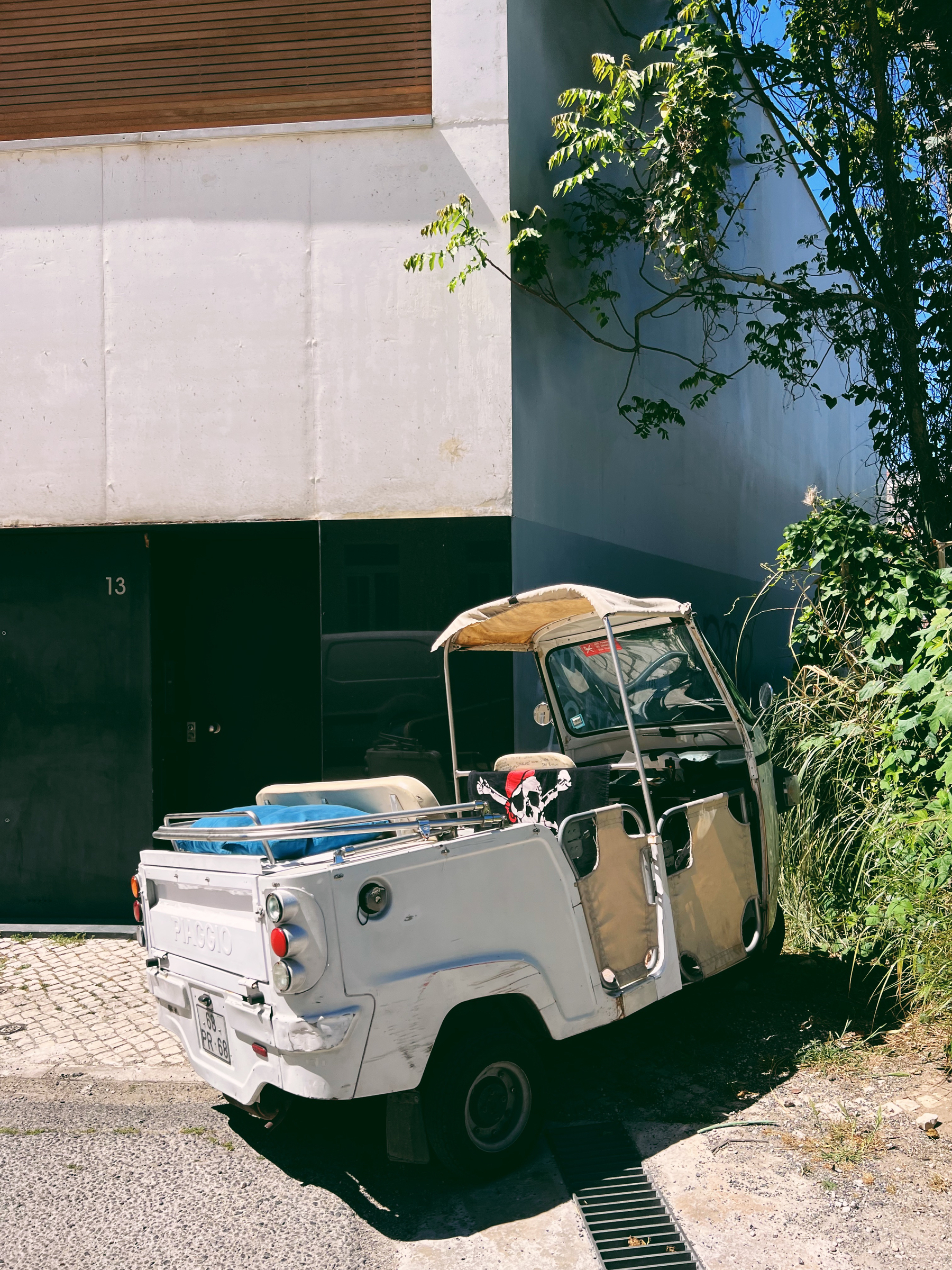 a tuk-tuk with a pirate’s skull flag, parked in the street
