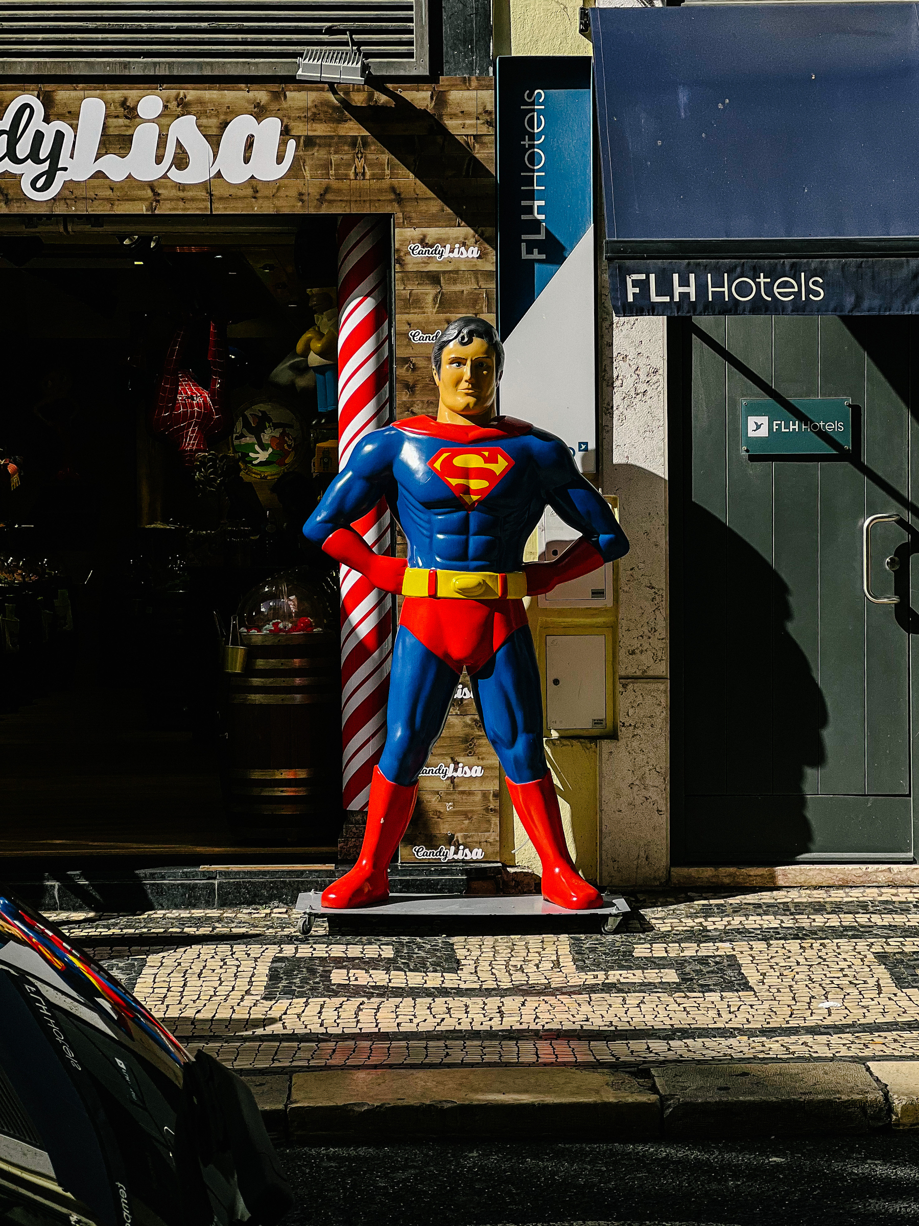 A Superman figure, human sized, in front of a shop. 