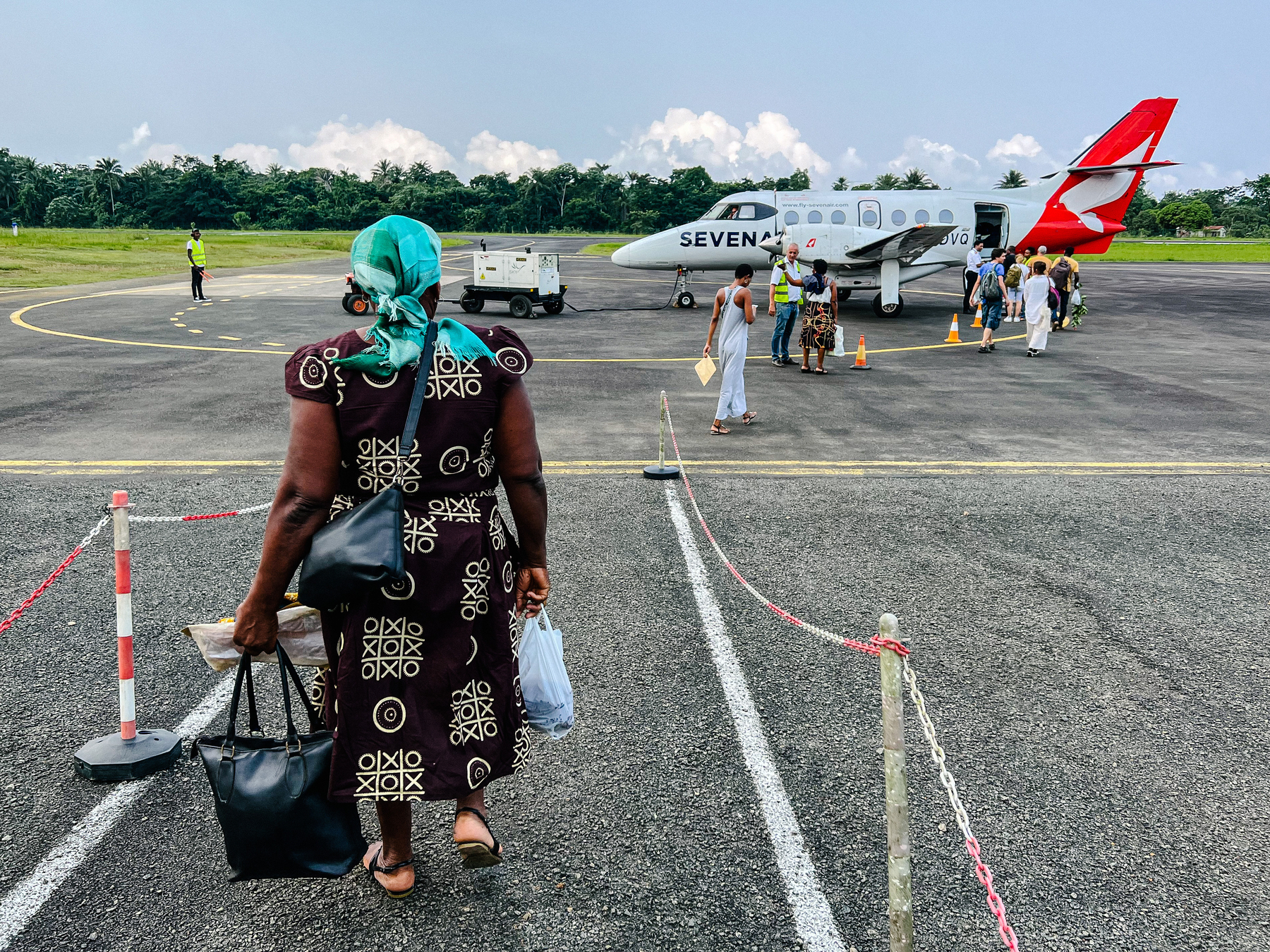 A woman prepares to board a tiny plane. Her dress has a tic tac toe dress.  