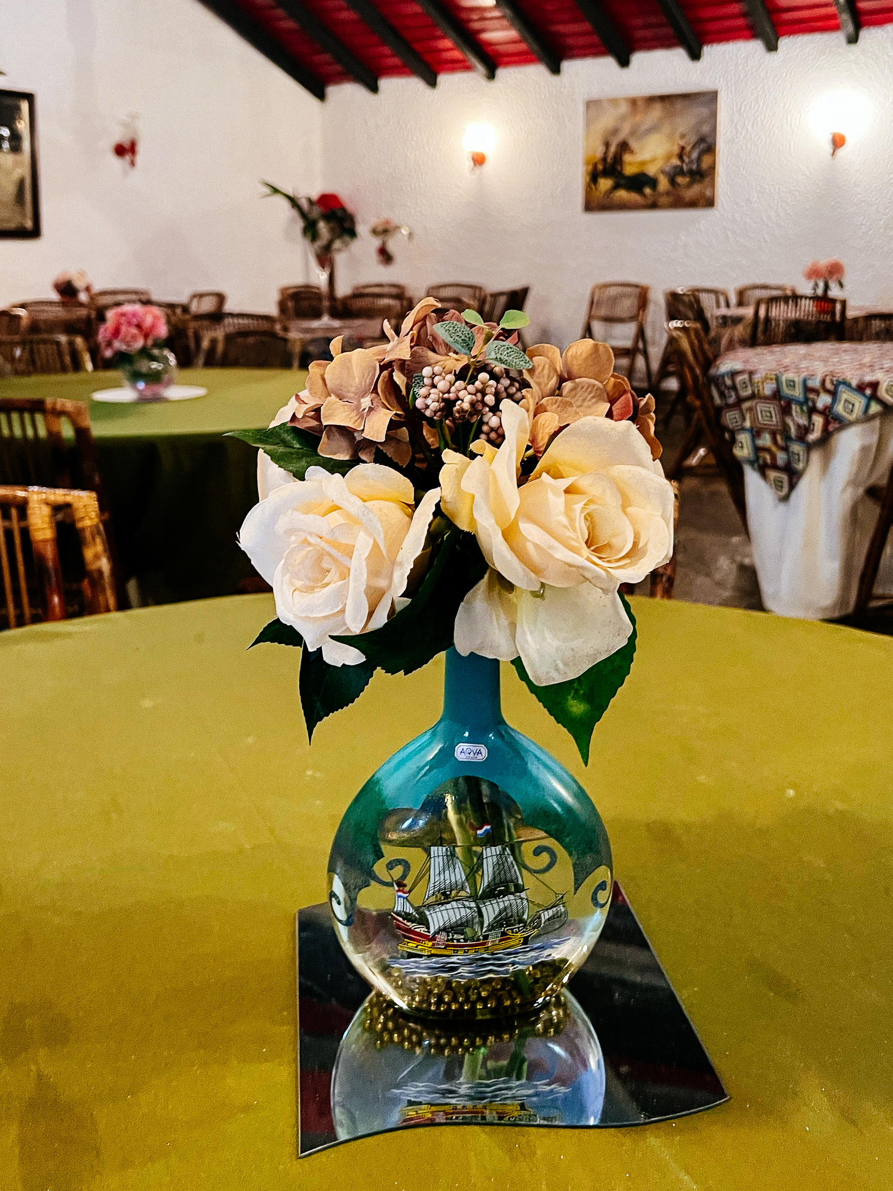 A kitschy restaurant room, with fake flowers on the tables. 