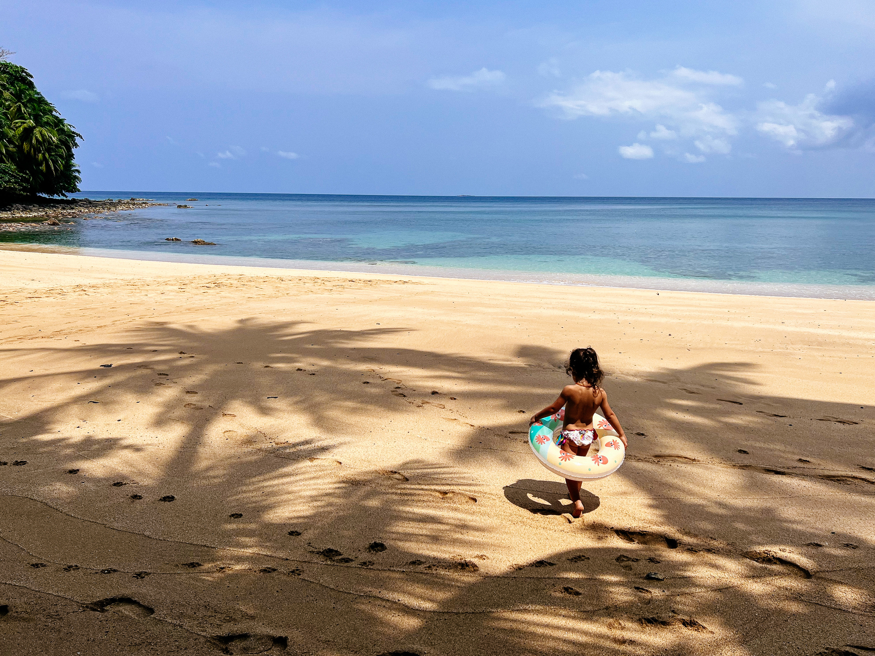 A toddler walks on a deserted beach. 