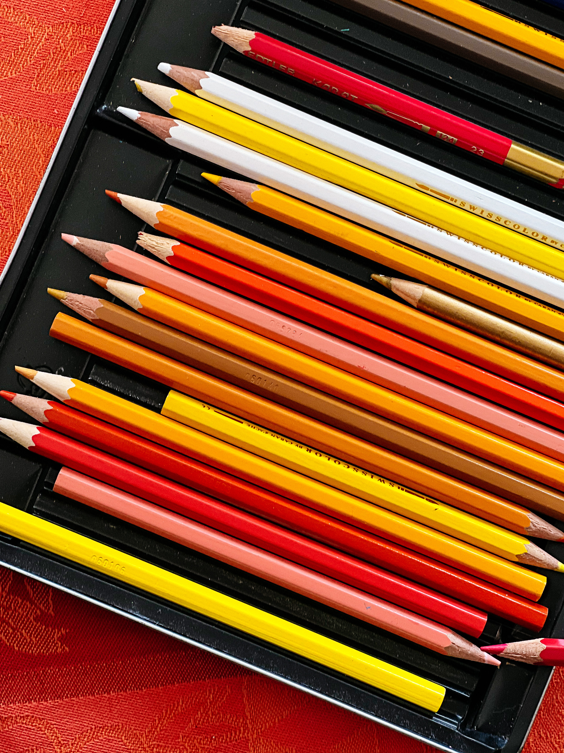 A box of pencils. Yellow, orange, and red ones. A couple of white ones. 