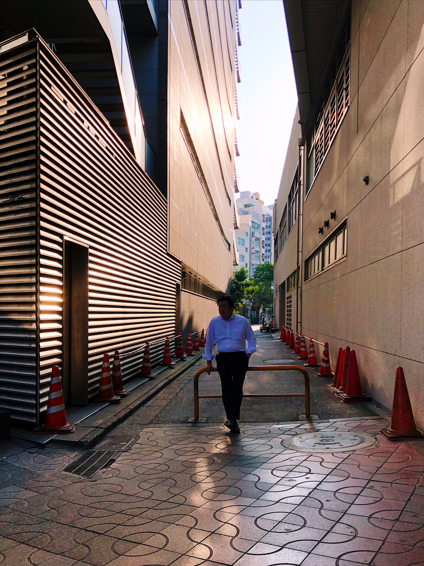 A smoker enjoys a cigarette in a smoking area. Alley, with tall buildings on both sides. 