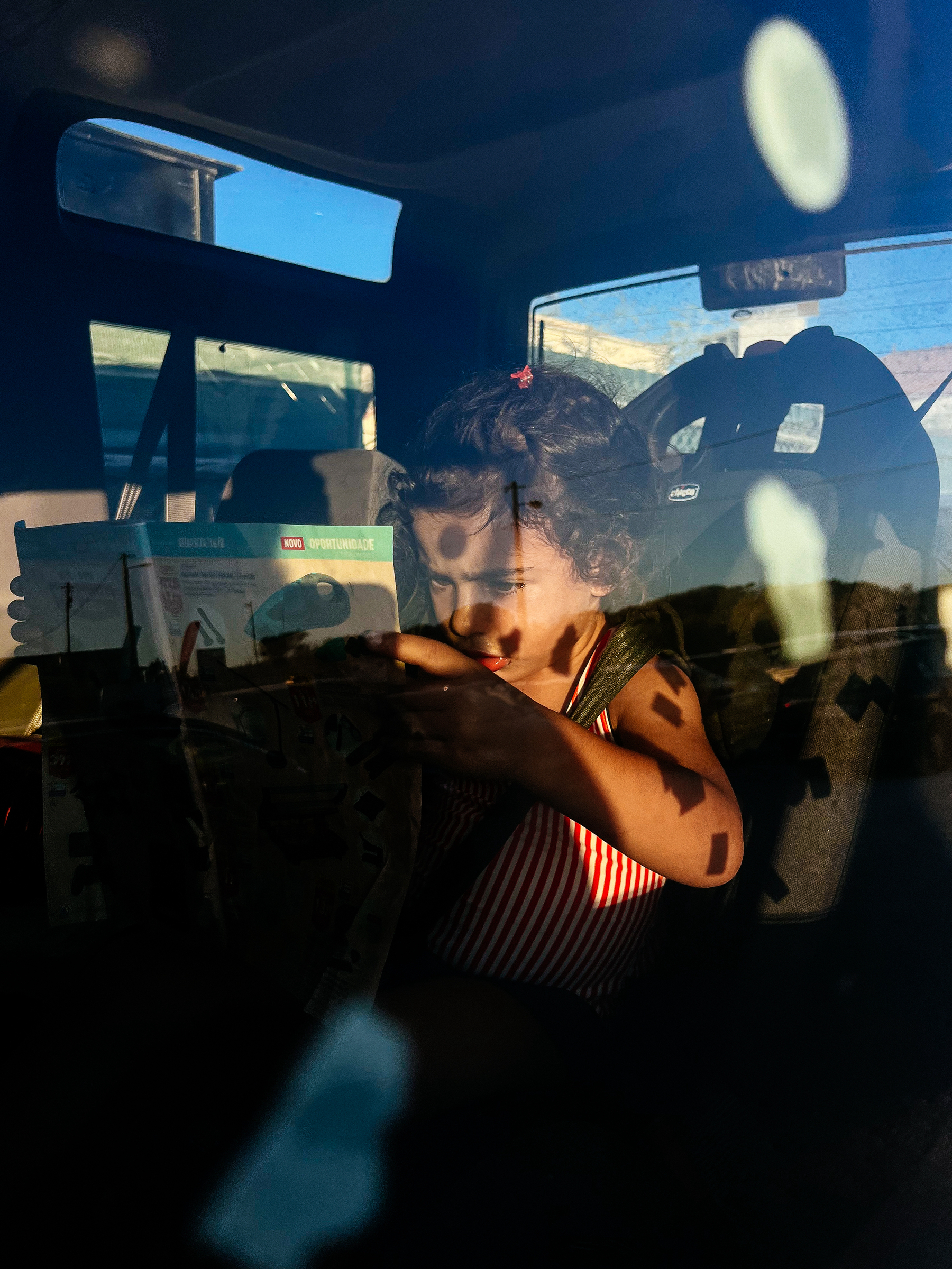 A girl reading while seating in a car. 