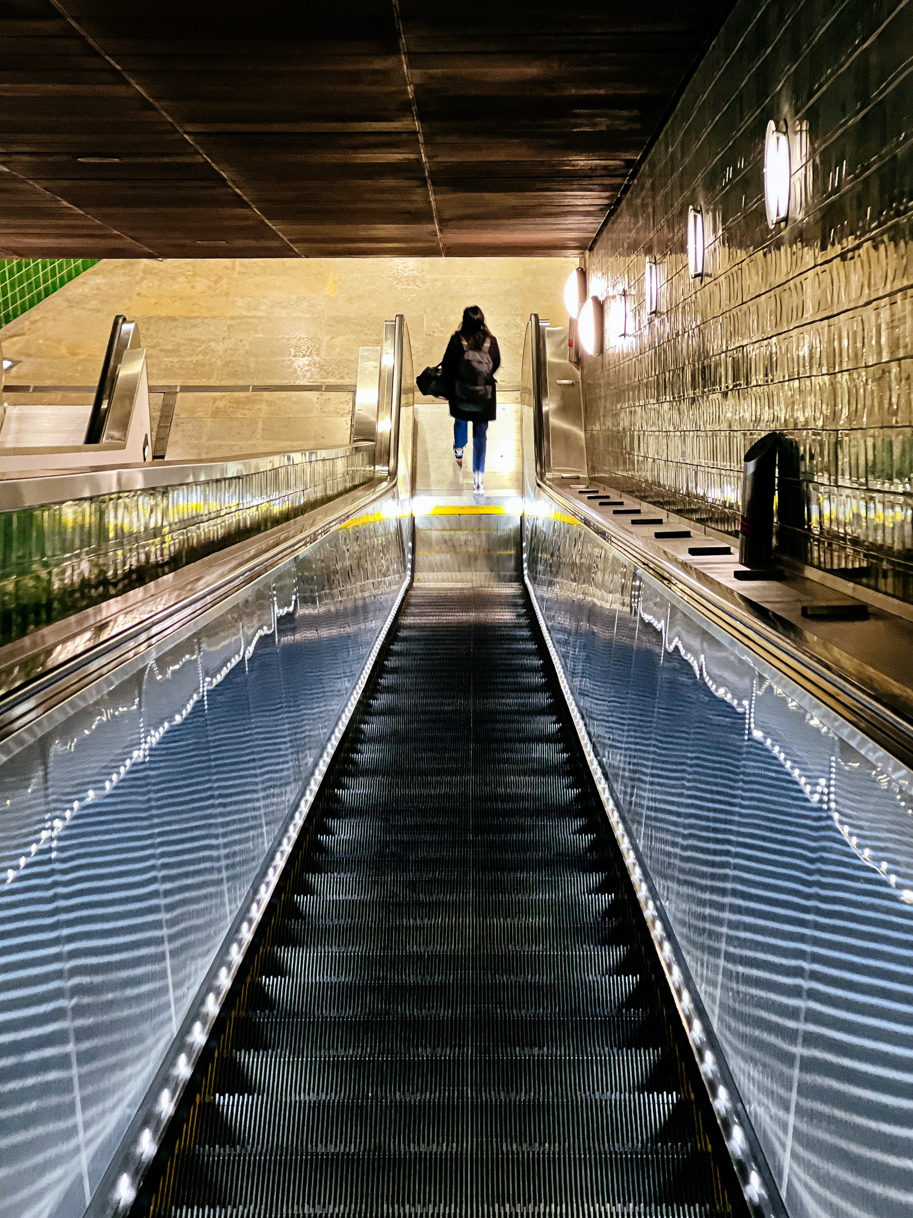 A person at the bottom of an escalator, seen from above. 