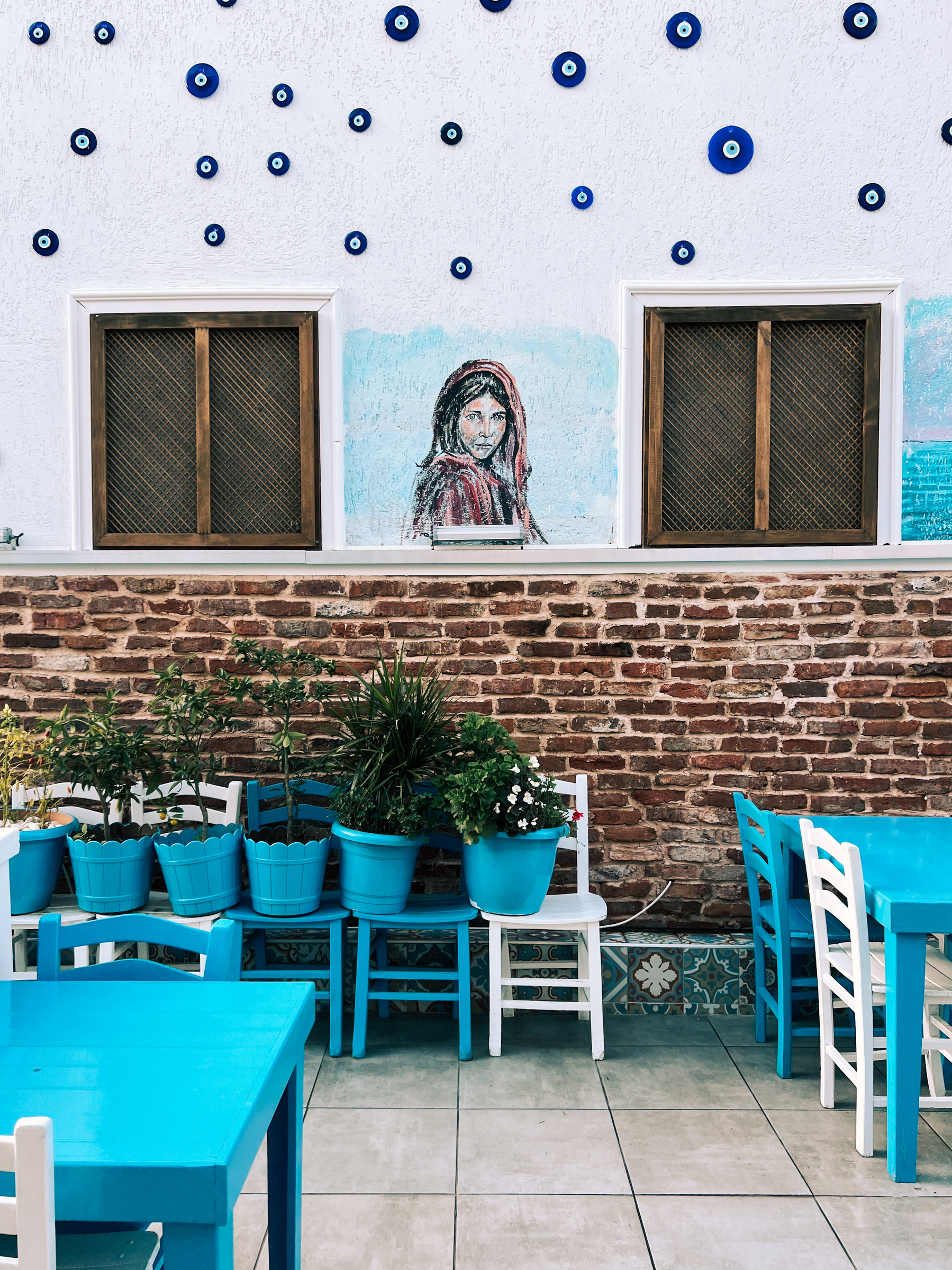 Restaurant patio, with a painting trying to replicate Steve McCurry’s Afghan Girl. 