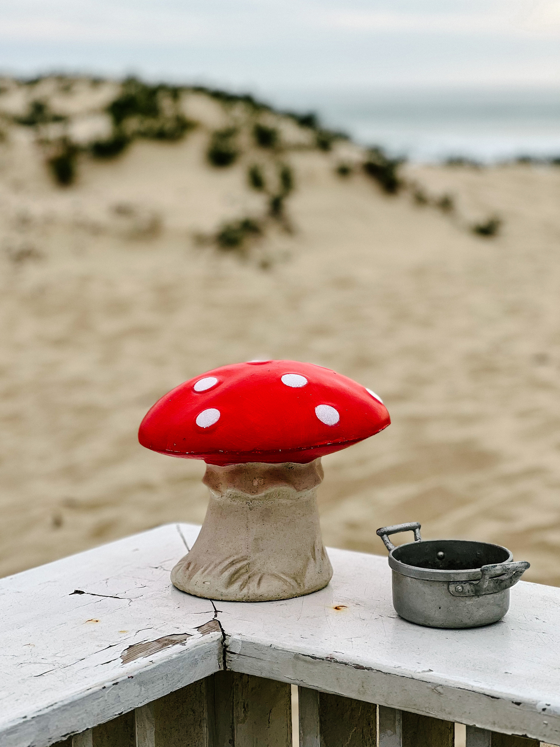 A ceramic mushroom stands outside, near the beach. 