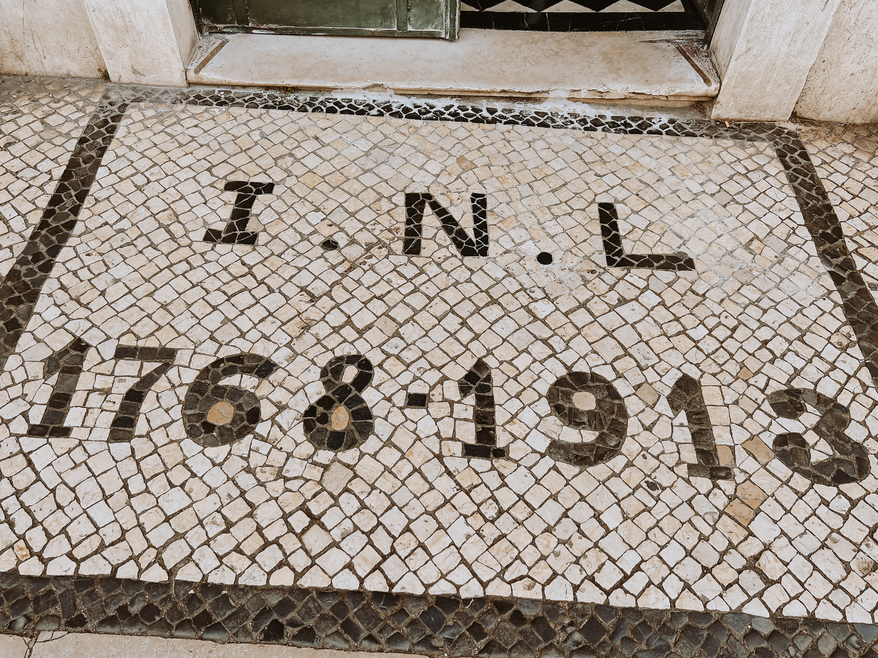 Looking down on a sidewalk, with Portuguese calçada. Simple one, with “I.N.L 1768-1913” written on the floor. 