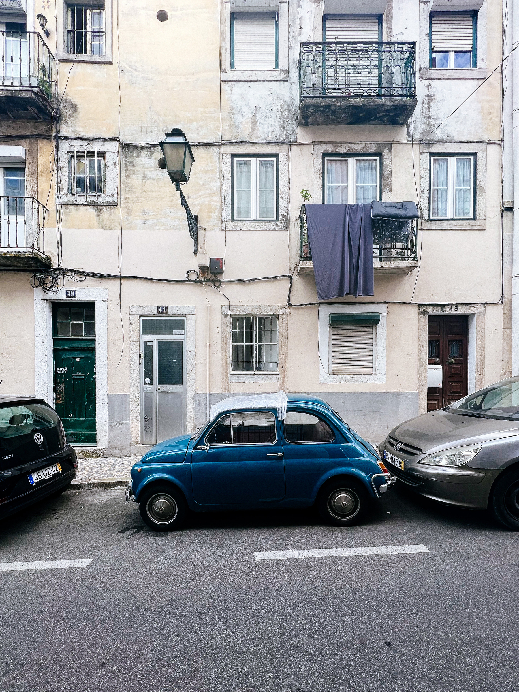 a very small car is park in front of a old building.