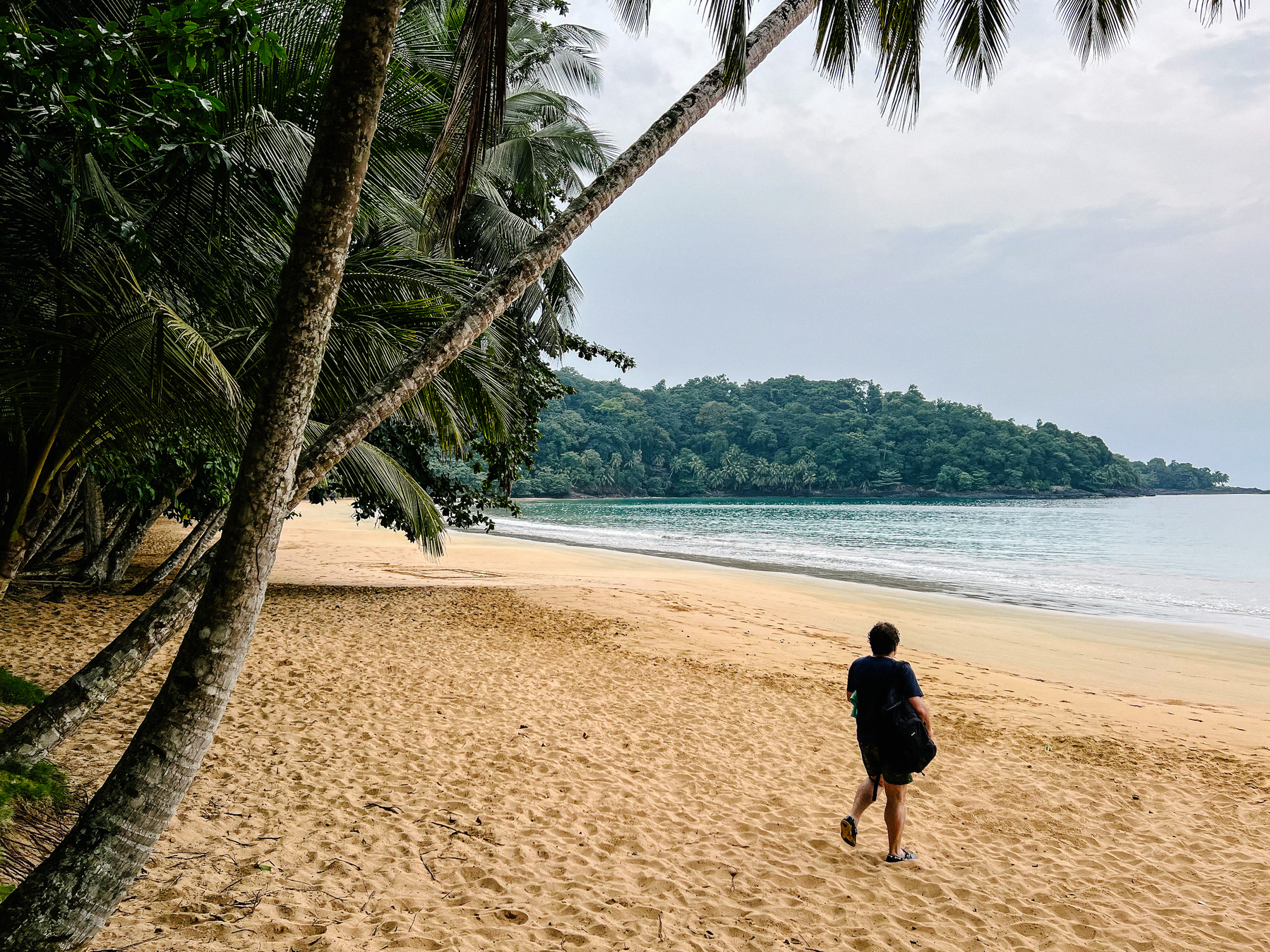 A man walks into a deserted tropical beach. 