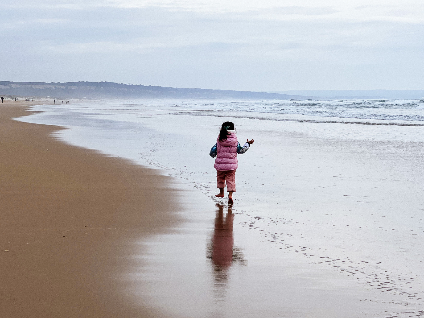 A toddler runs in an empty beach. 