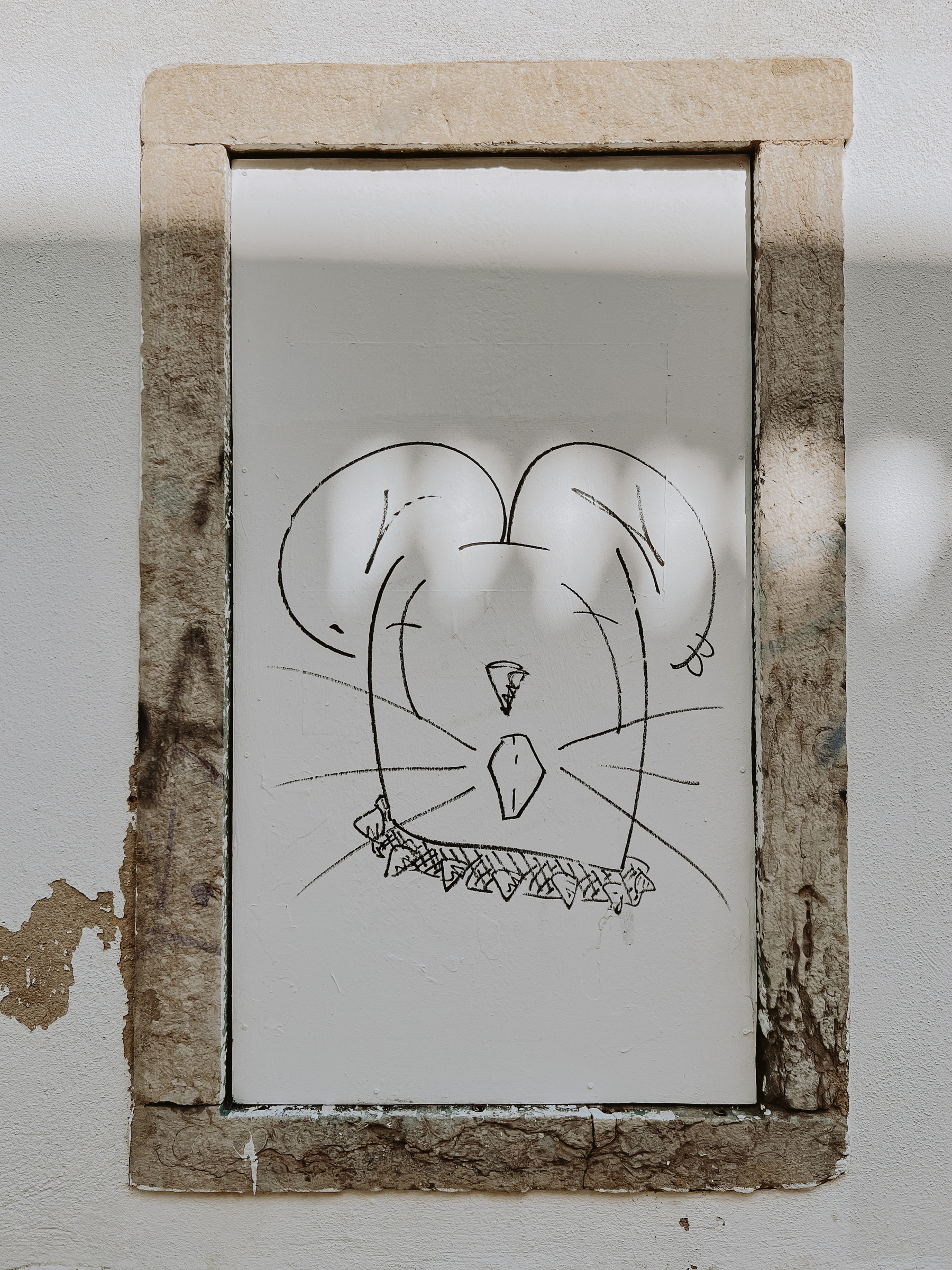 A cartoony mouse drawn on a wall. 