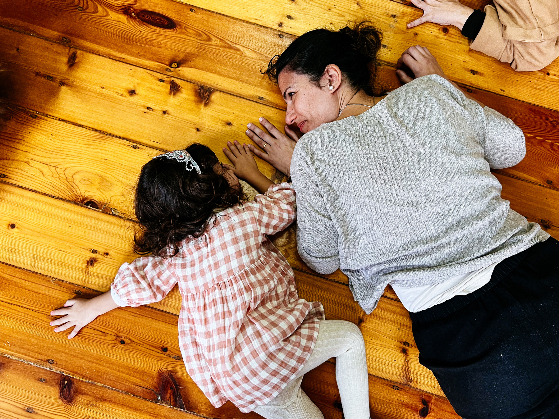 A toddler and her mom on the floor, during a dance class. 