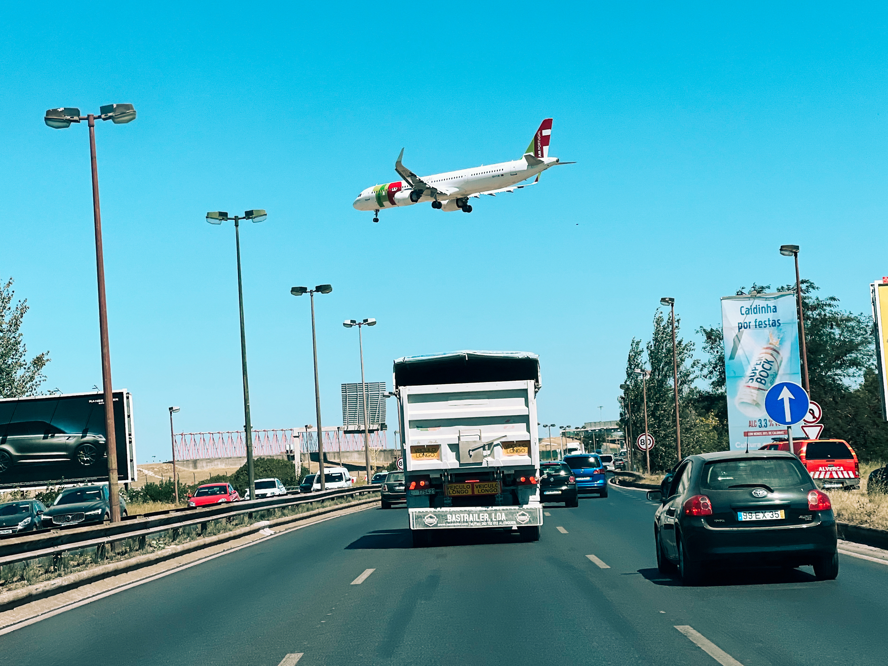 An airplane flies over a busy road. 
