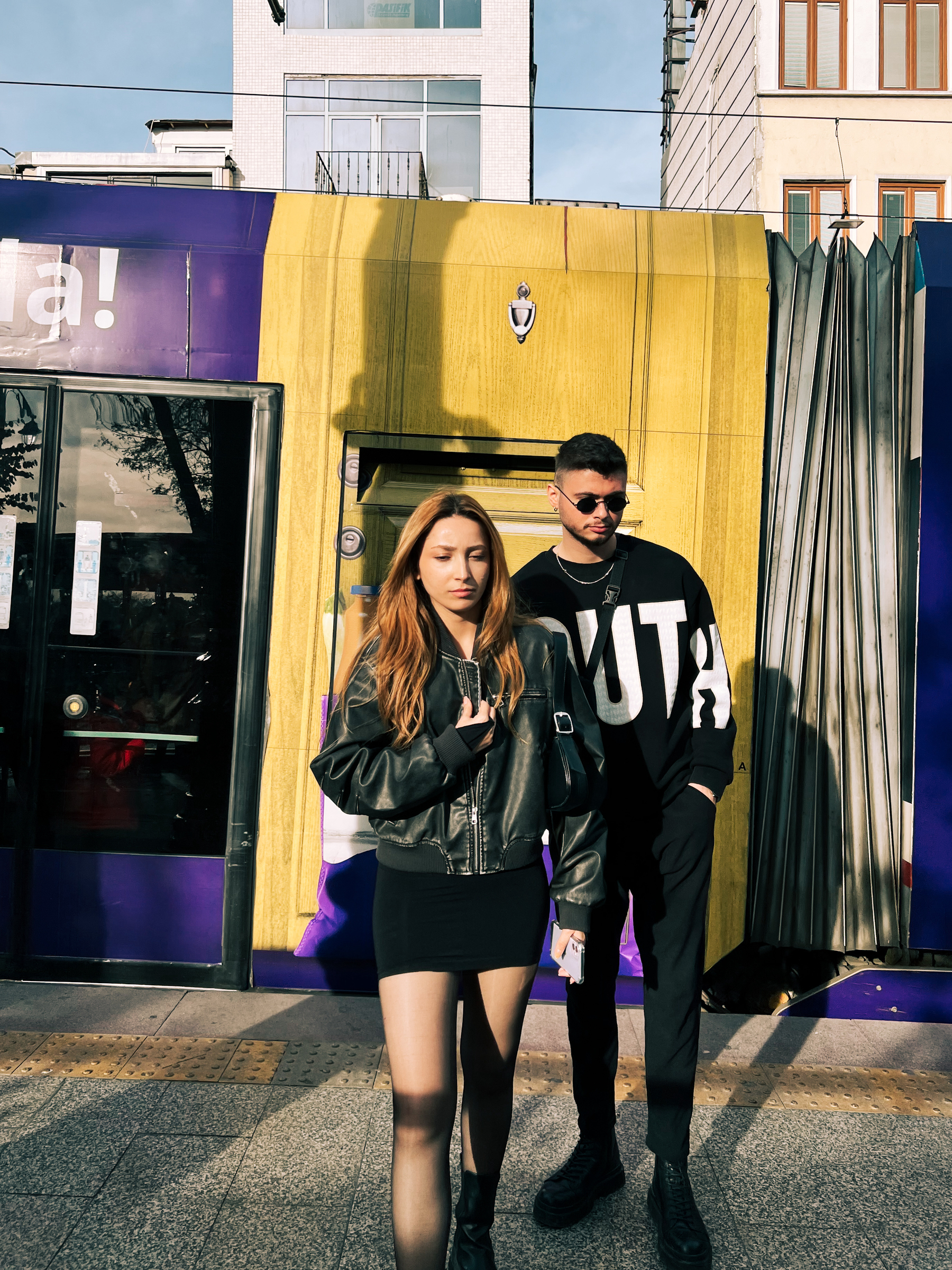 A young couple steps out of a tram, catwalking. 