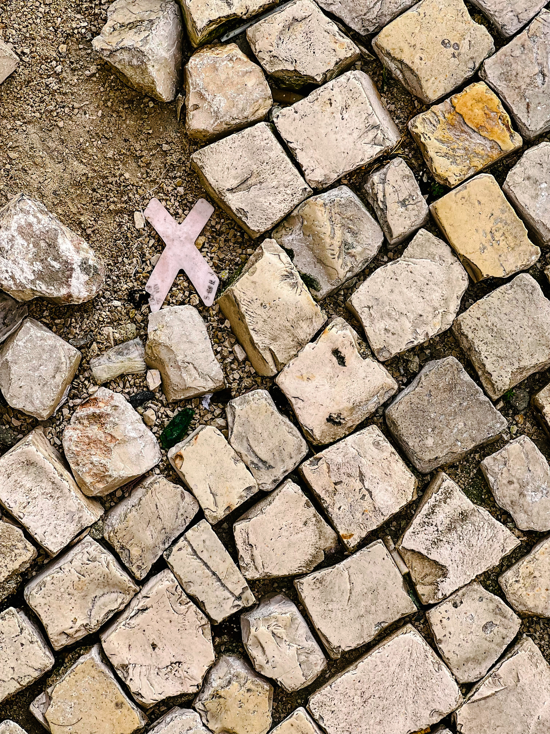 A “X” on the ground, in the middle of Portuguese calçada. 