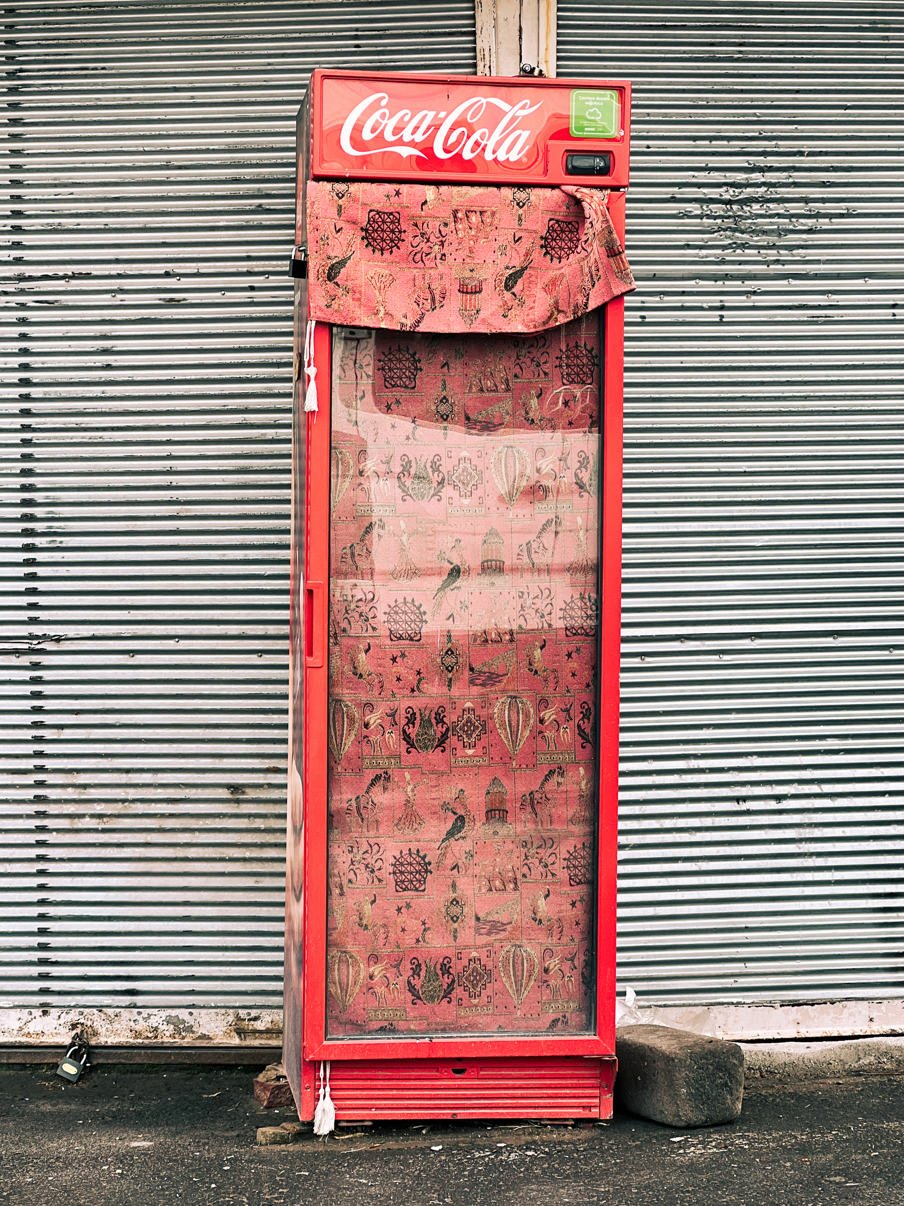A vintage Coca-Cola machine, covered with red fabric. 
