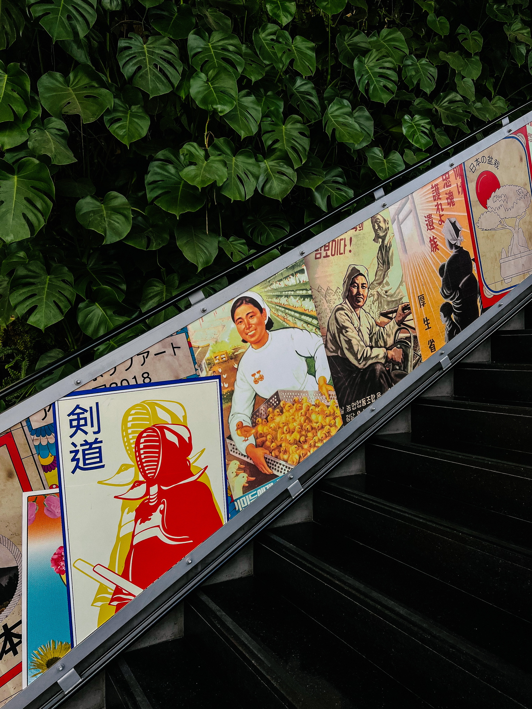 A stairway, with Asian inspired posters on the way up. 