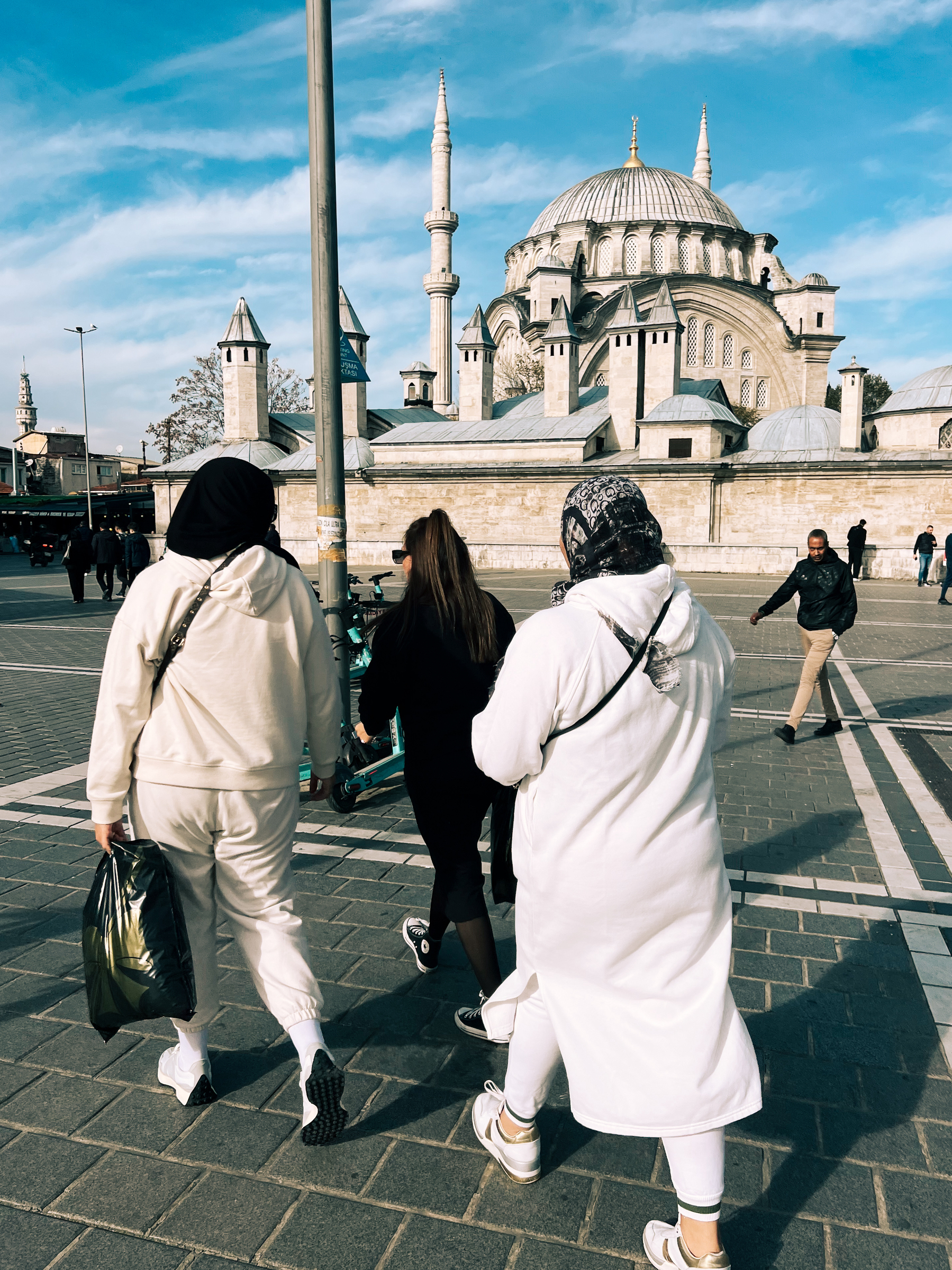 Women walk next to a mosque. 