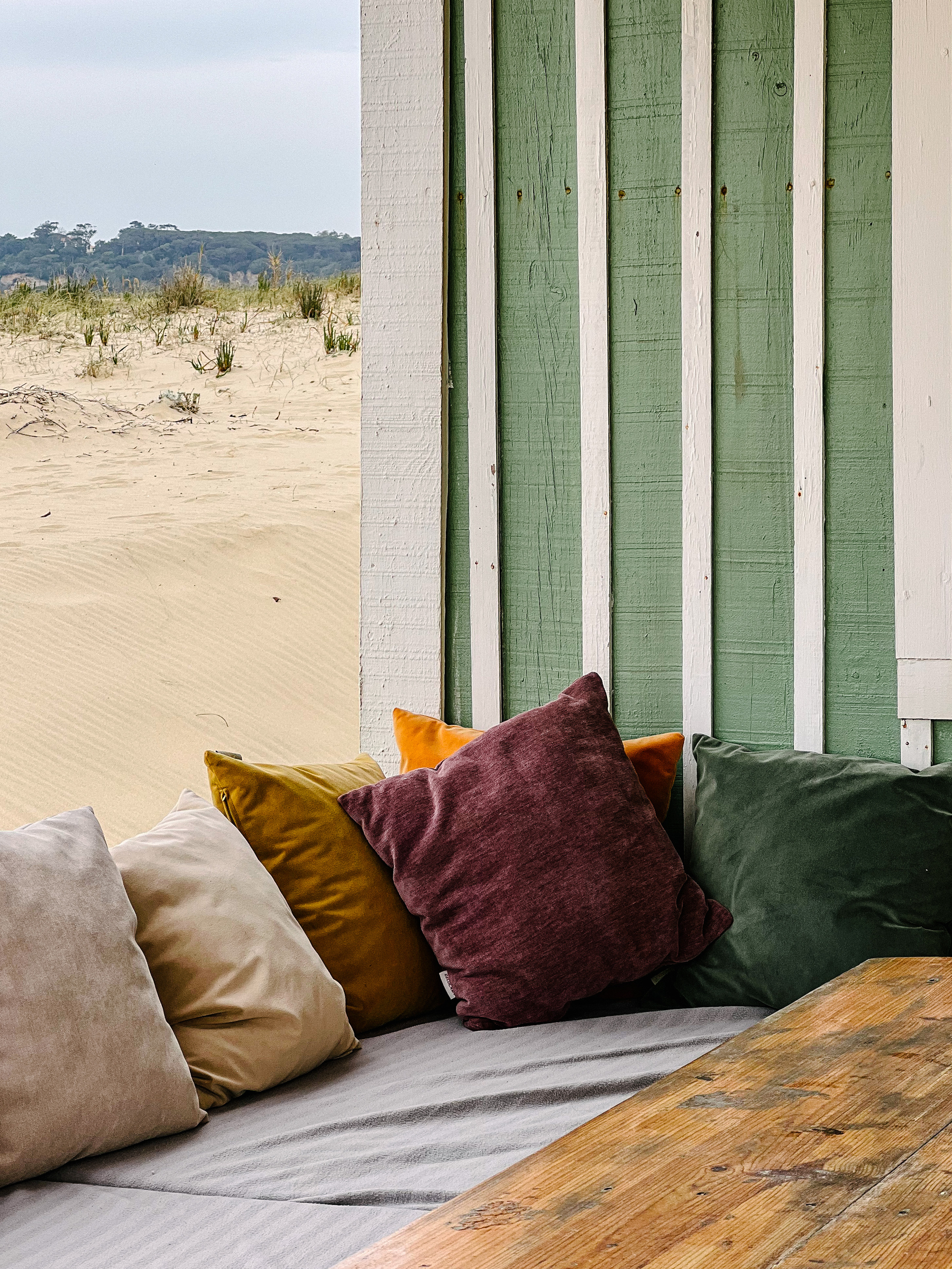 Pillows next to a green wall, with sand in the background. 