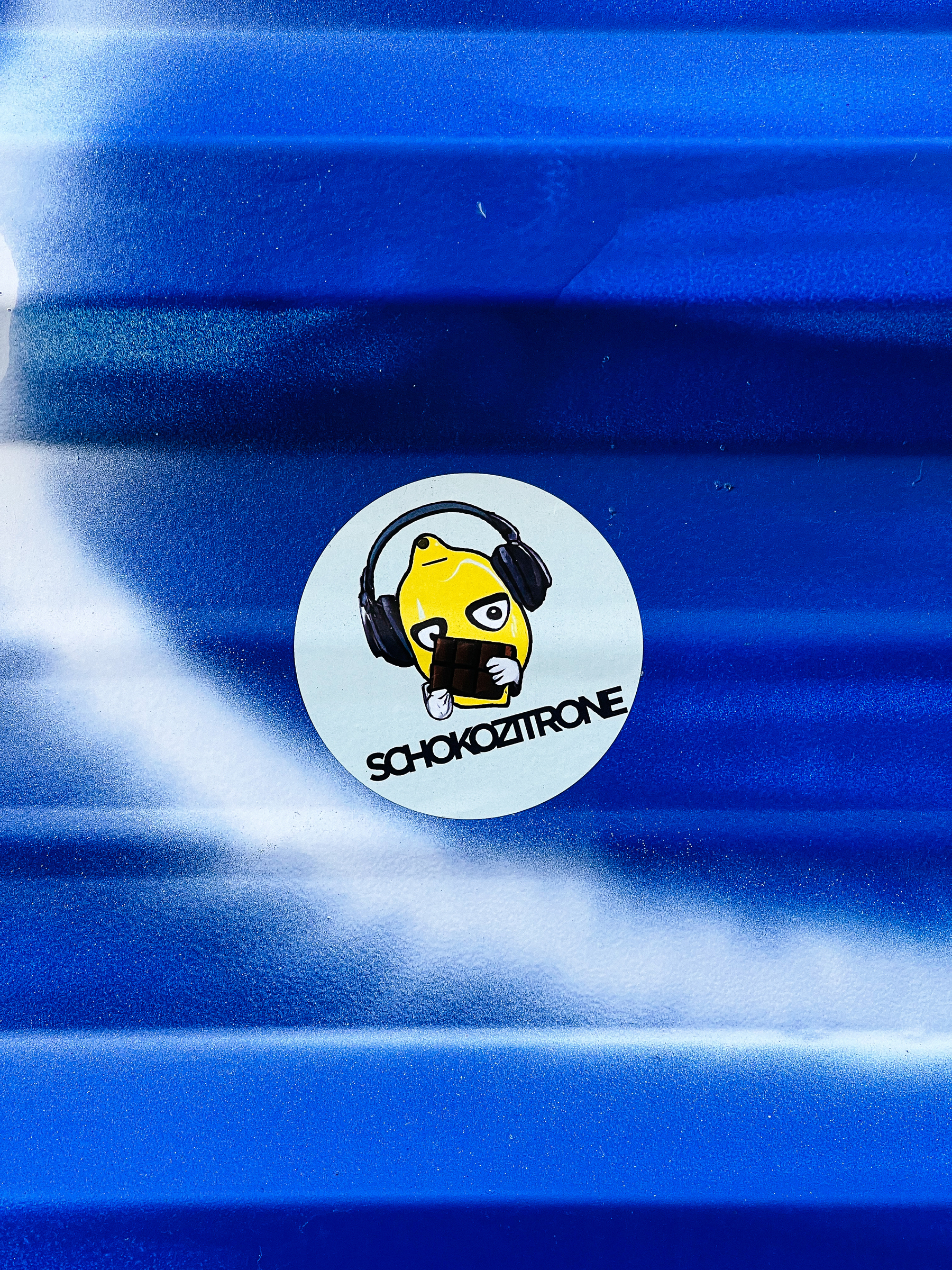 A lemon wearing headphones, holding a chocolate bar. &ldquo;SCHOKOZITRONE&rdquo;. It&rsquo;s a sticker. 
