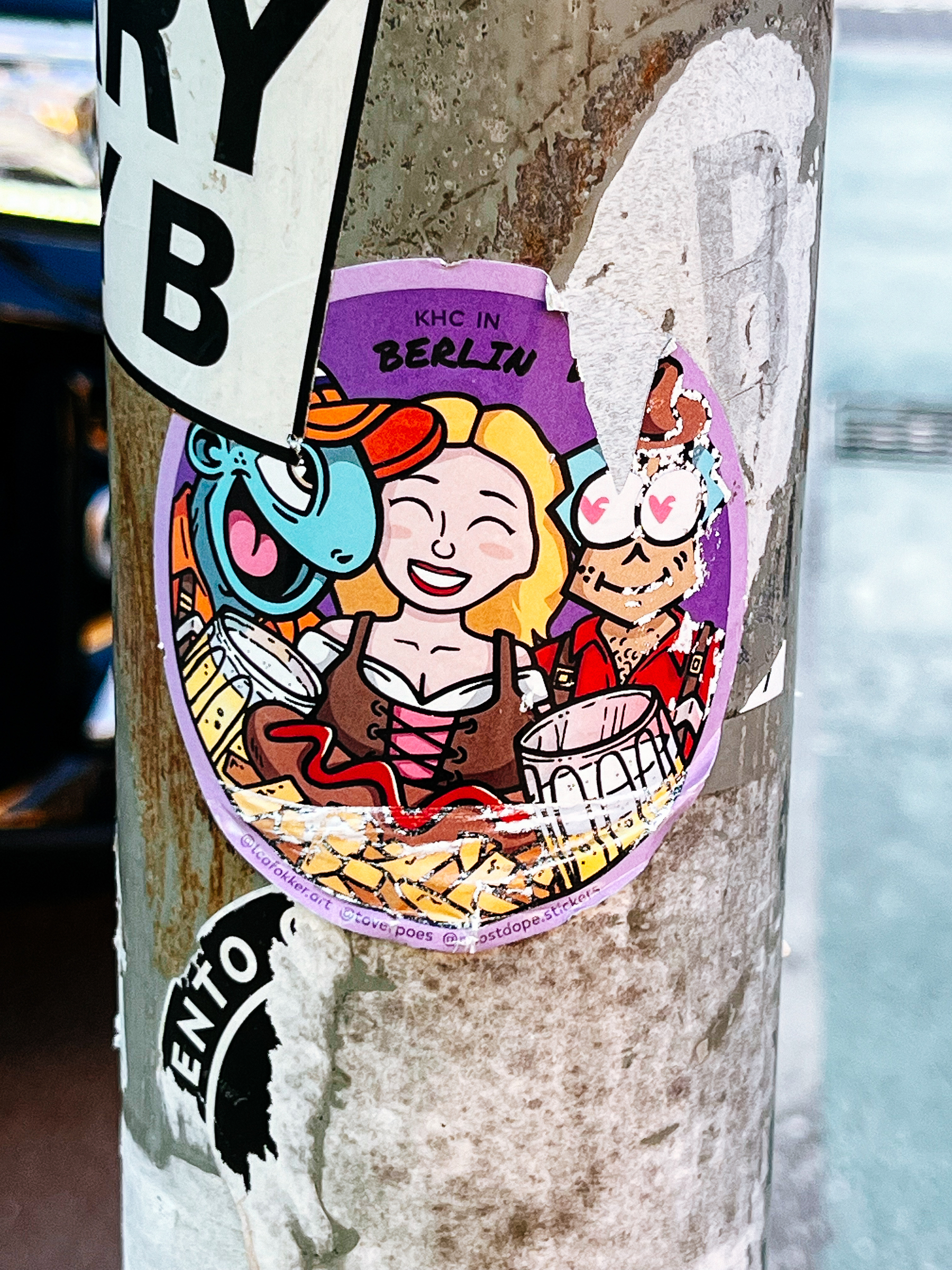 Drawing, in cartoon style, of a girl dressed in traditional German outfit, with beer and a hot dog. Two alien like figures are looking at her. A sticker. 
