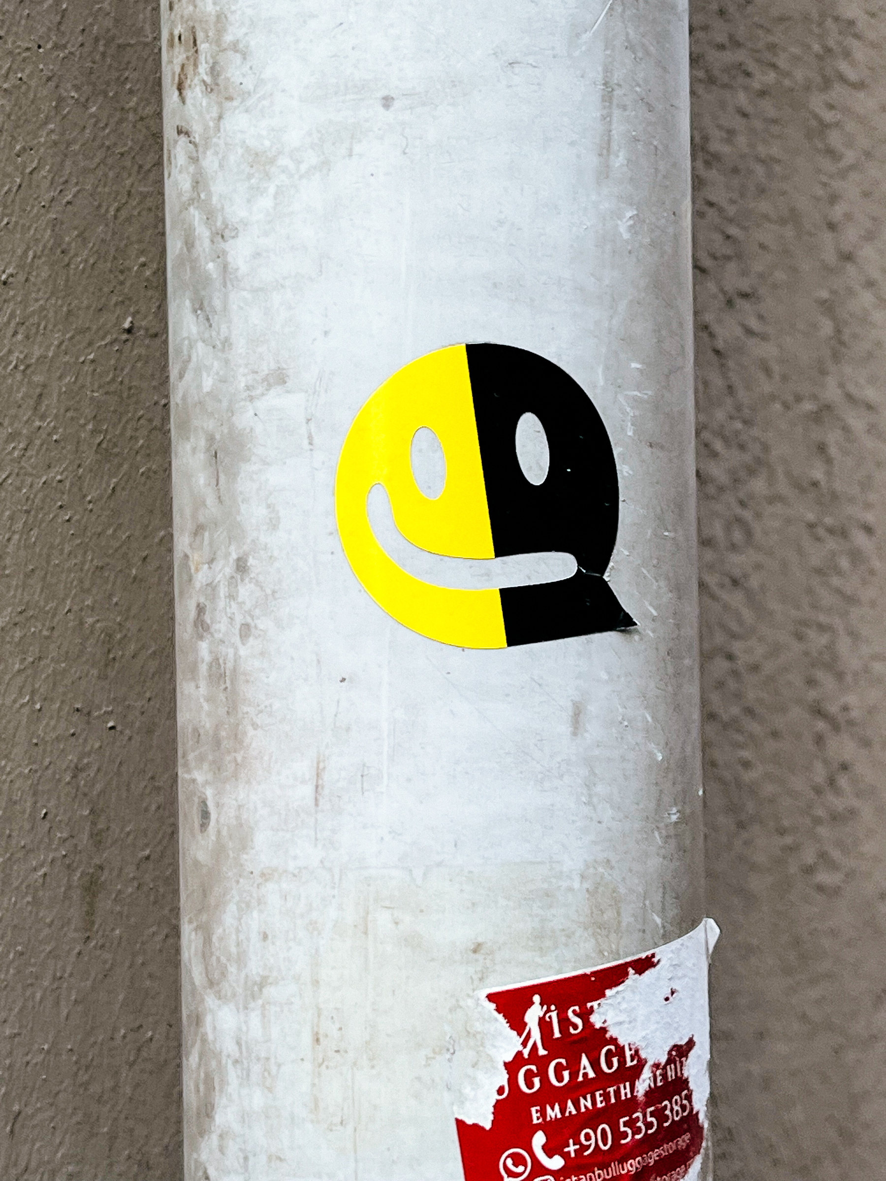 A smiling emoji-like face, half yellow, half black. A sticker. 