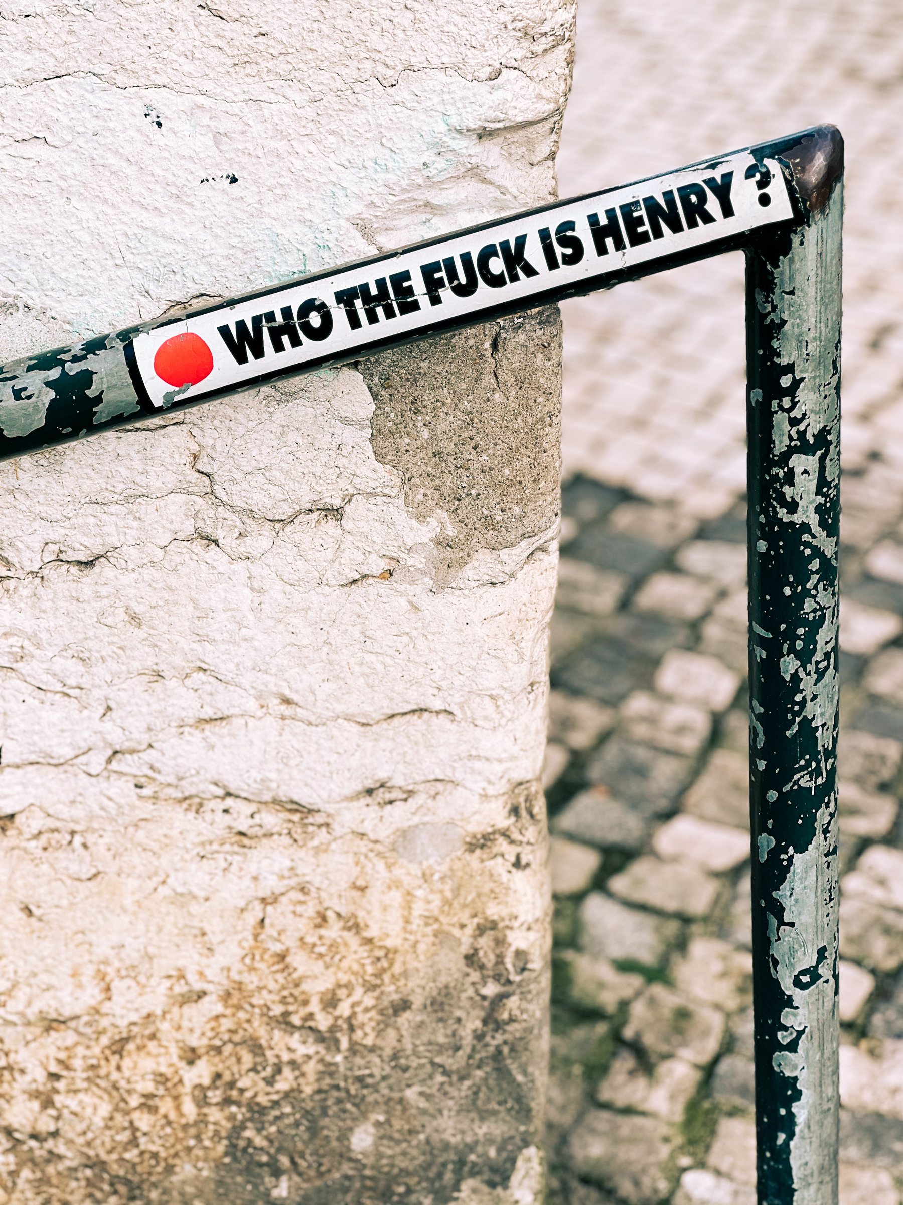 A metal barrier with a sticker that reads &ldquo;WHO THE F*** IS HENRY?&rdquo; affixed to it.