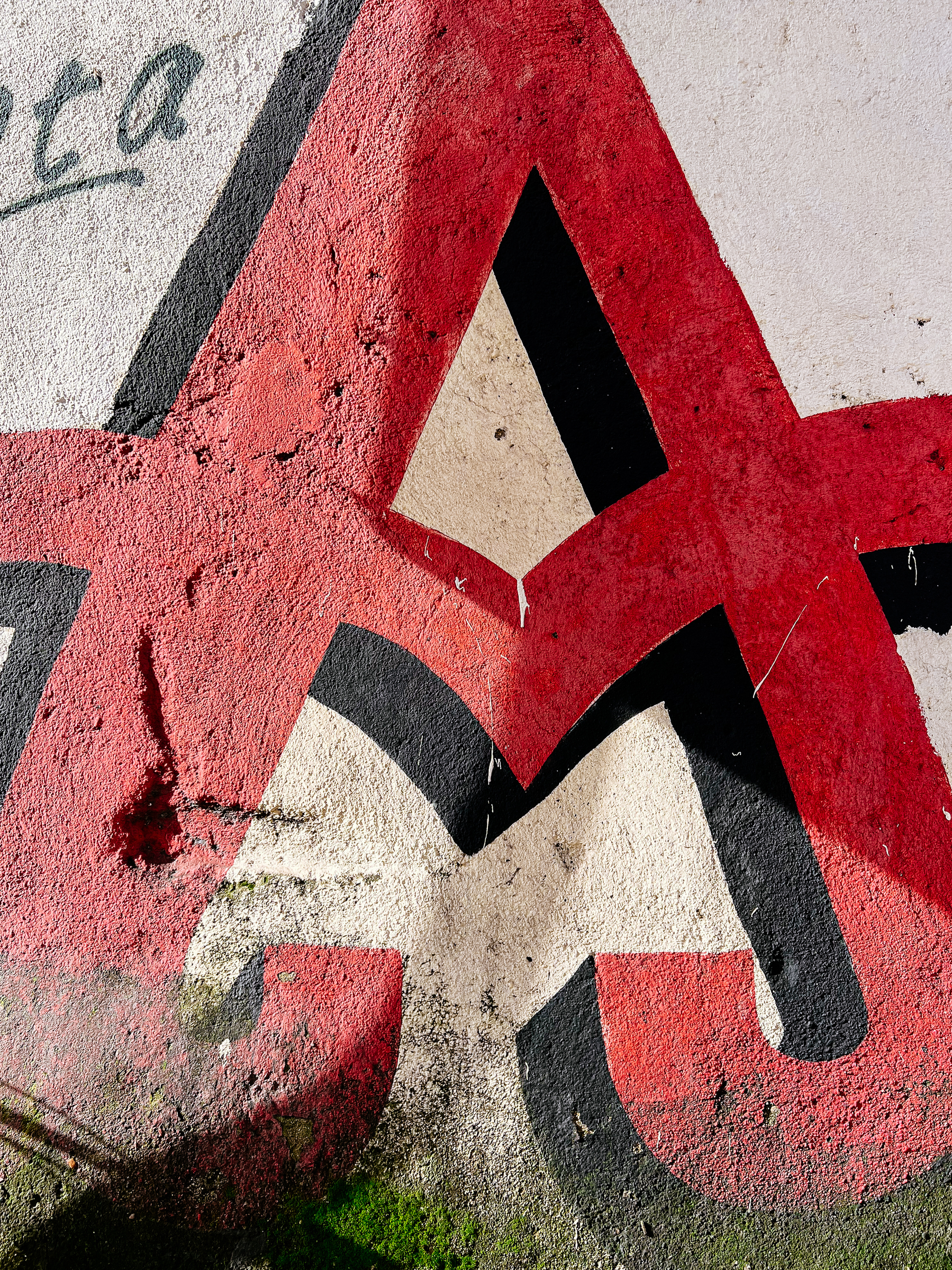 Graffiti of a red and black letter A on a textured wall.