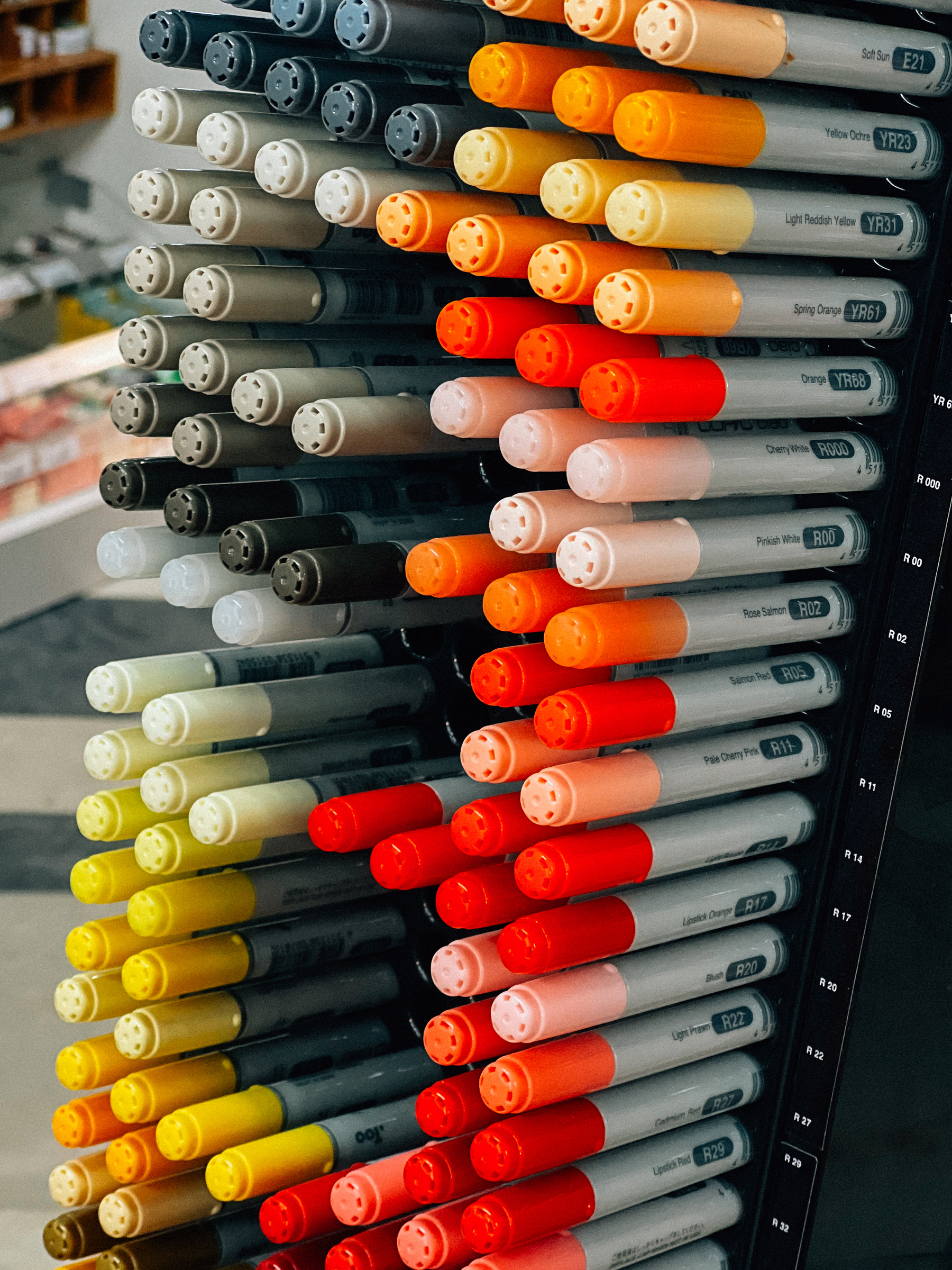 A collection of markers in a variety of colors, with caps showing, aligned in slots with color codes labeled on the right.