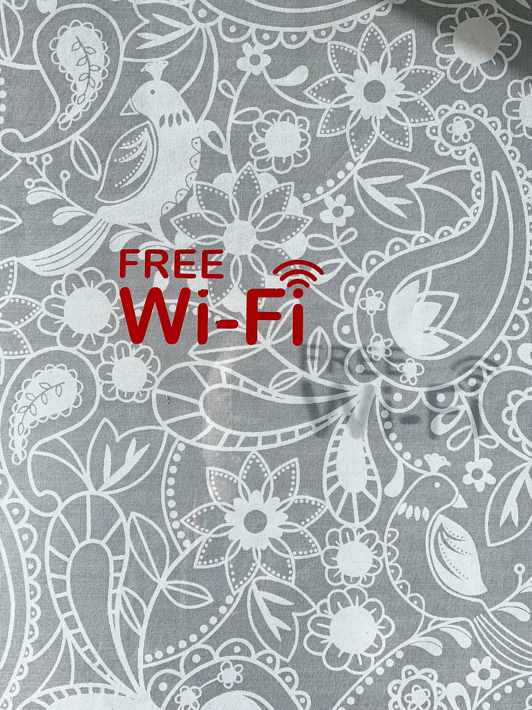 A patterned fabric background with &ldquo;FREE Wi-Fi&rdquo; text and Wi-Fi symbol superimposed in red.