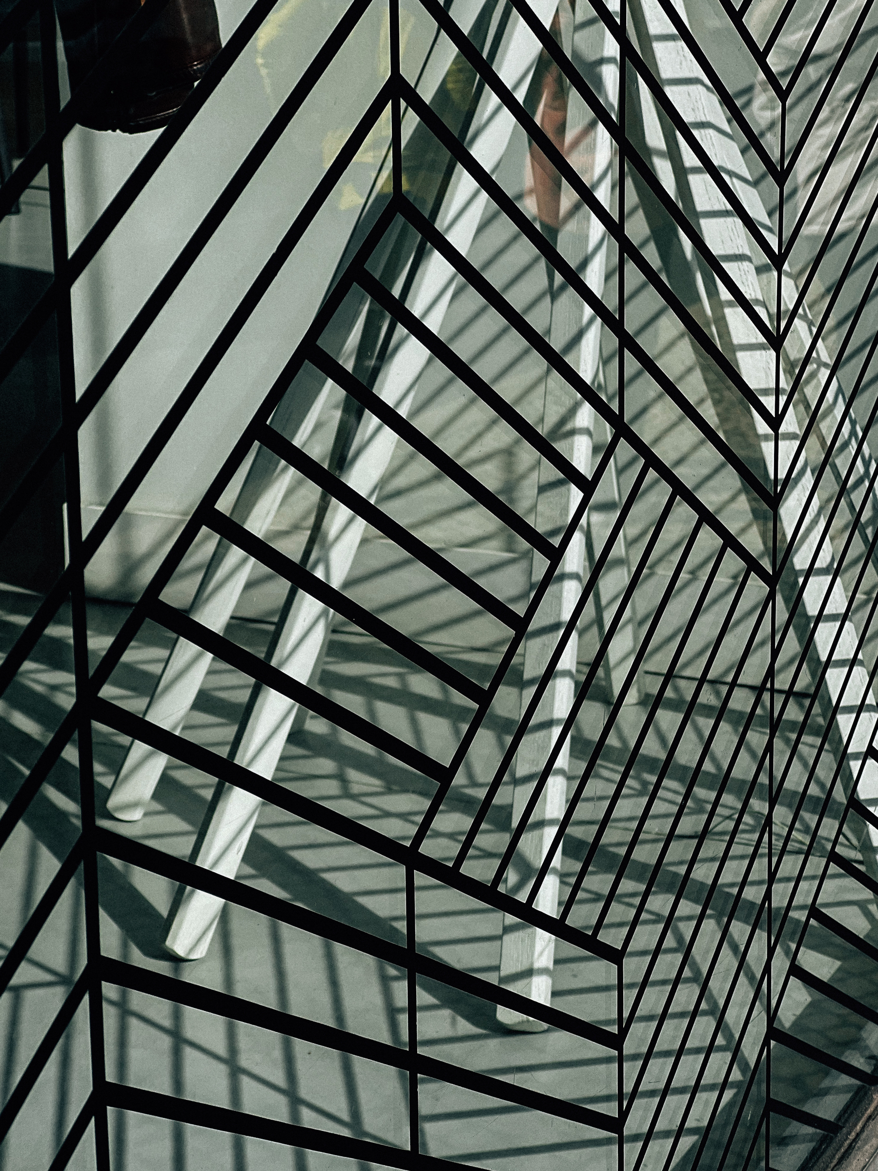 Abstract view of a modern building&rsquo;s geometric glass facade with a metal grid structure creating intricate patterns of light and shadow.