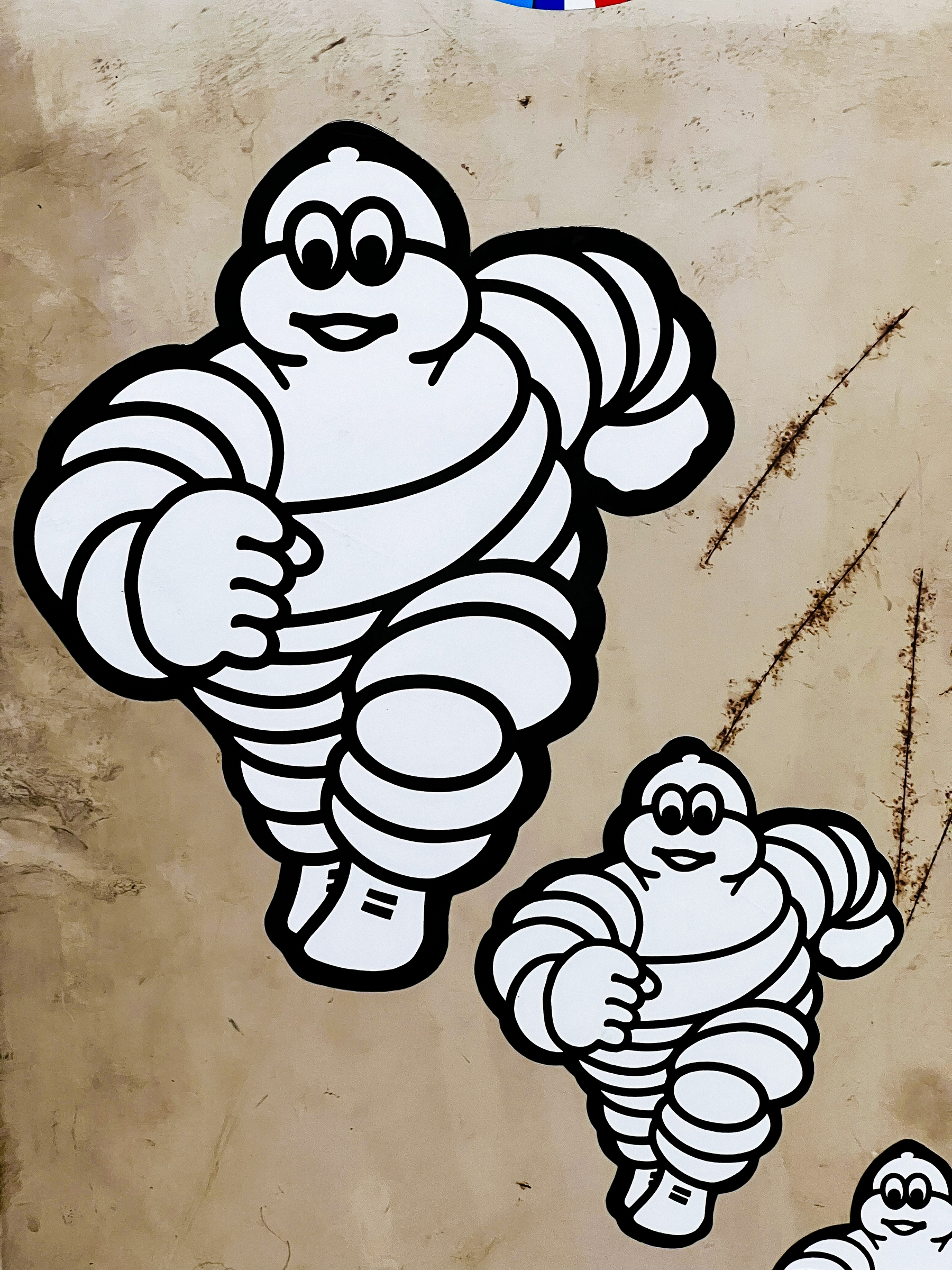 Three Michelin Men cartoon characters, decreasing in size, against a textured background.