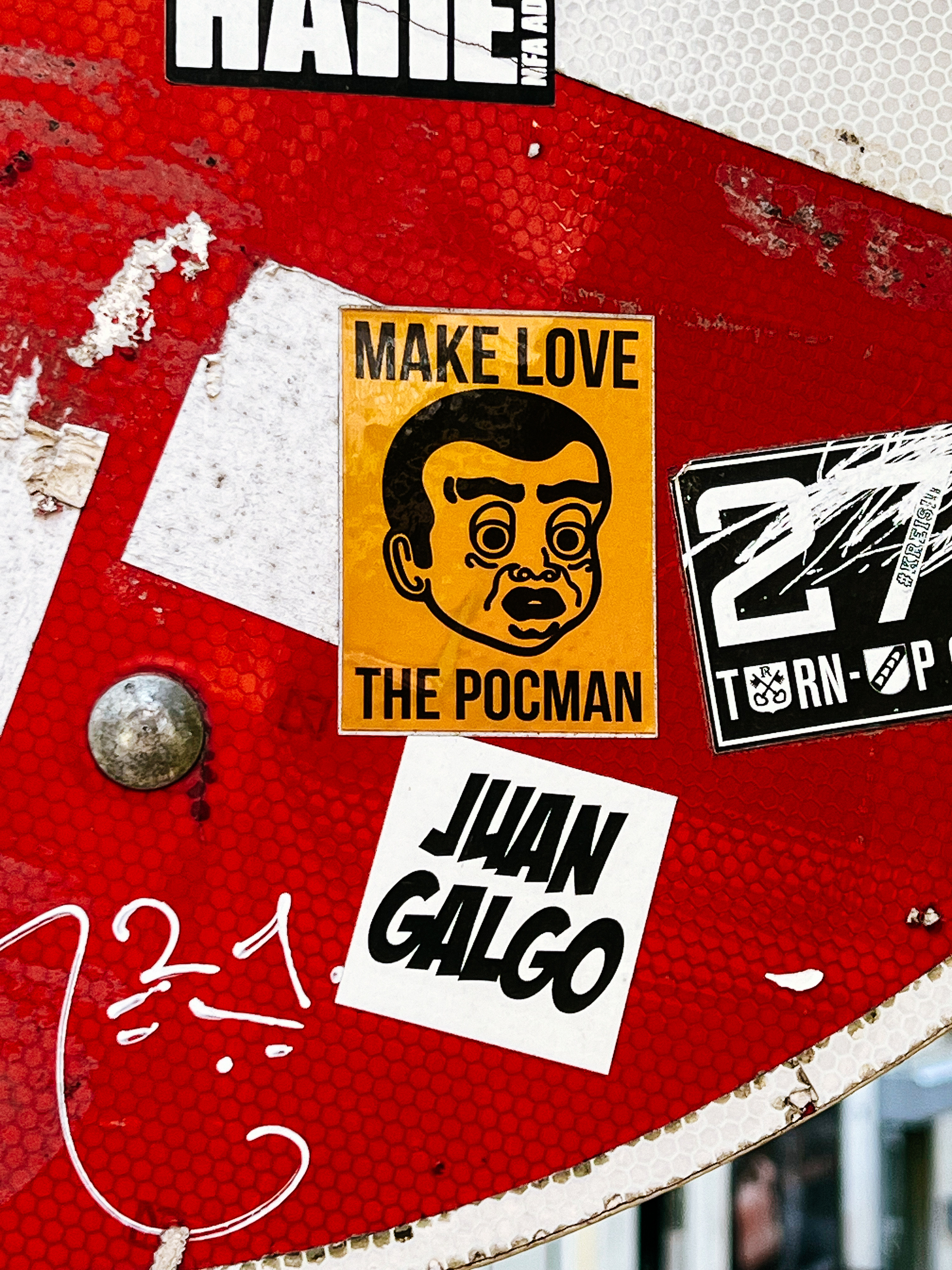 A sticker on a textured, red background reads &ldquo;MAKE LOVE / THE POCMAN&rdquo; accompanied by an illustration of a man&rsquo;s face.