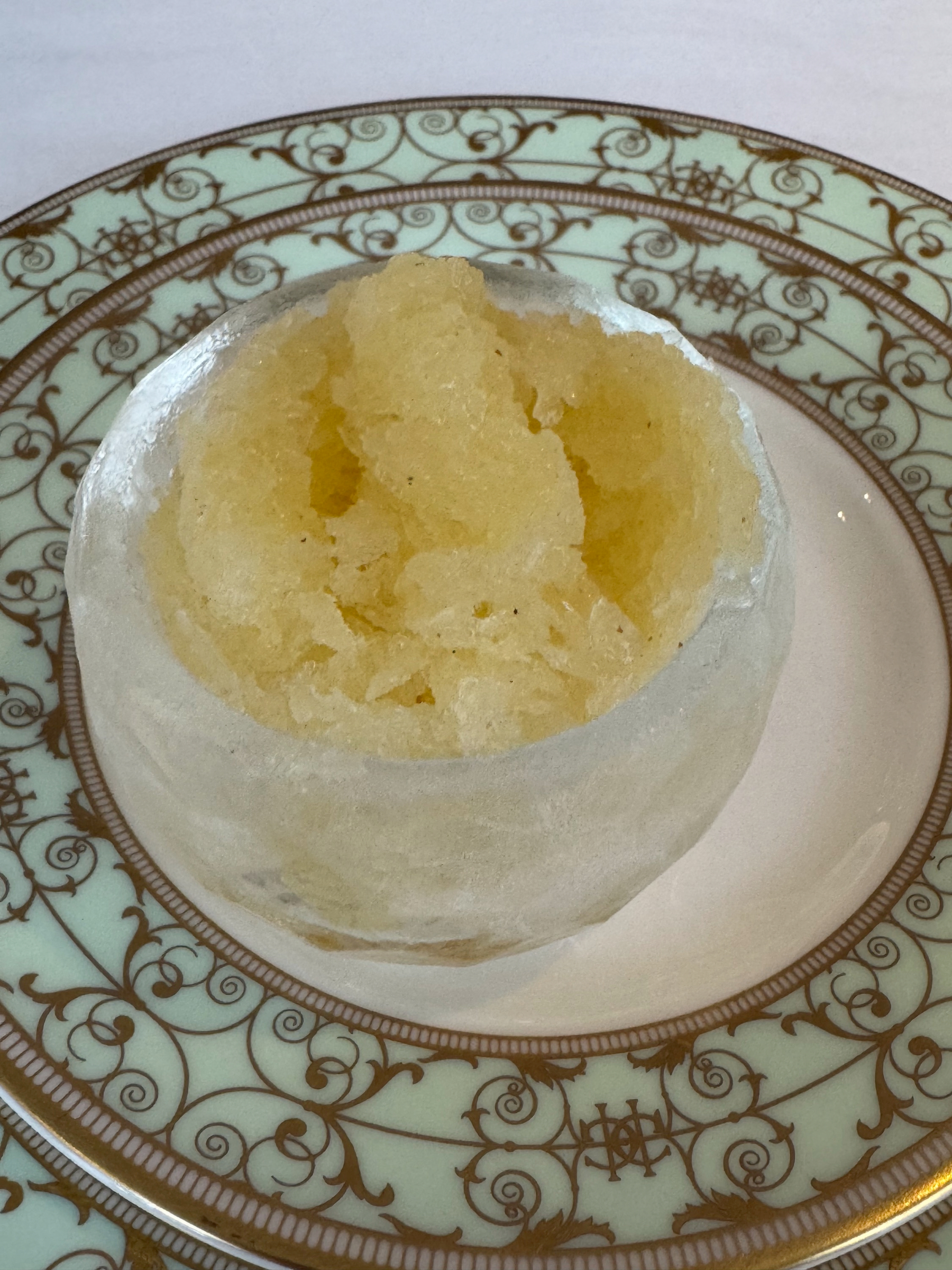 A pale yellow lemon sorbet served inside a hollowed lemon shell, frosty and crystalline. The icy texture and citrus color suggest a sharp, refreshing break between courses.
