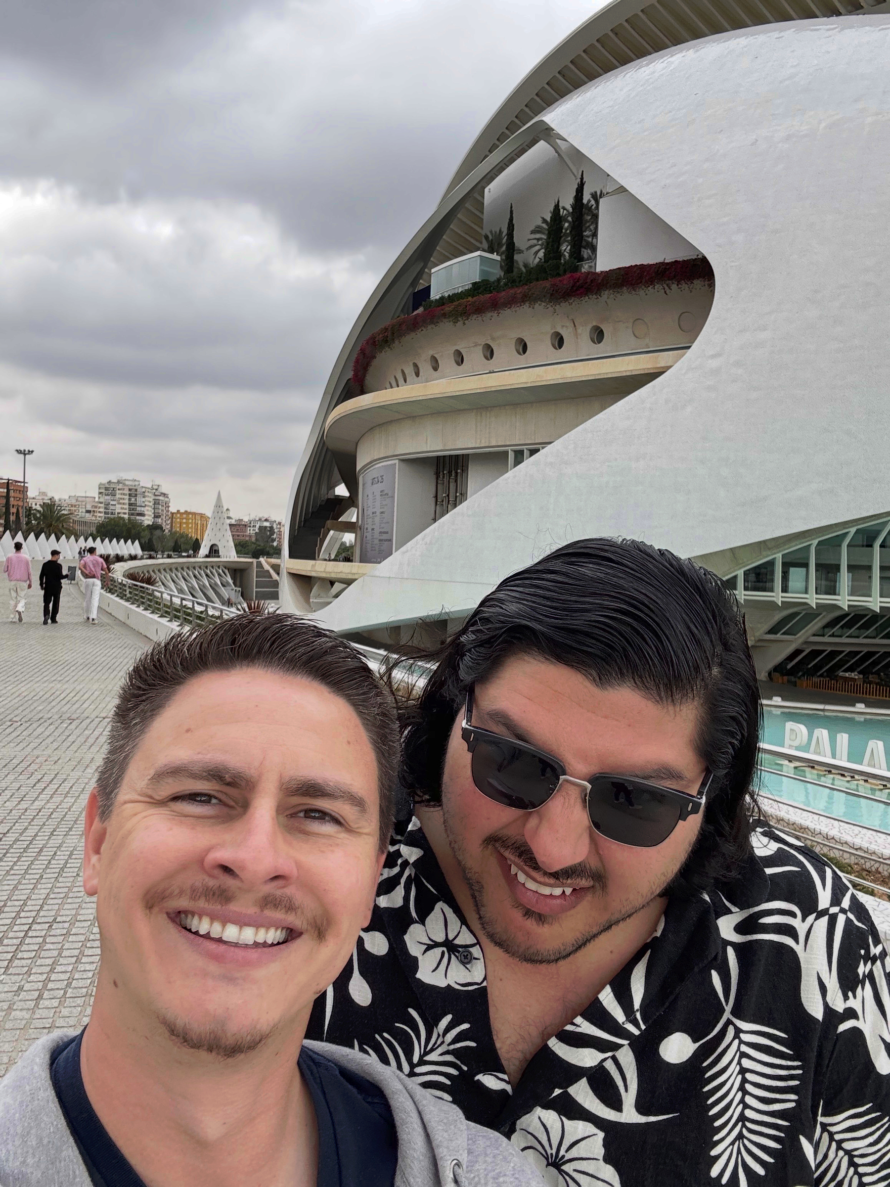 Hugo and I taking a close selfie on a walkway beside the City of Arts and Sciences, with sweeping white modern architecture curving behind us under an overcast sky.